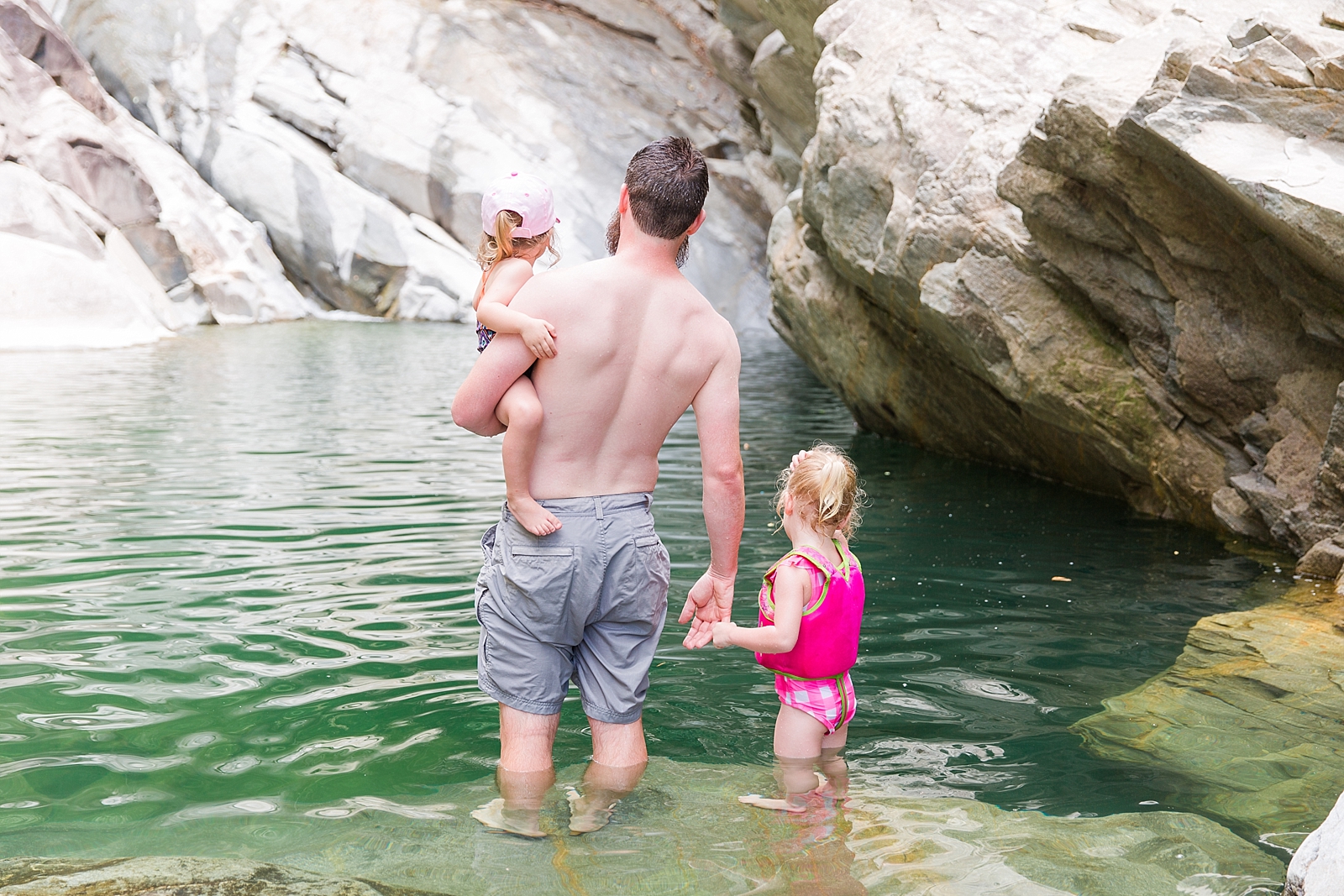 Nantahala Lake dad holding daughter in one arm and holding other daughters hand wading in water photo