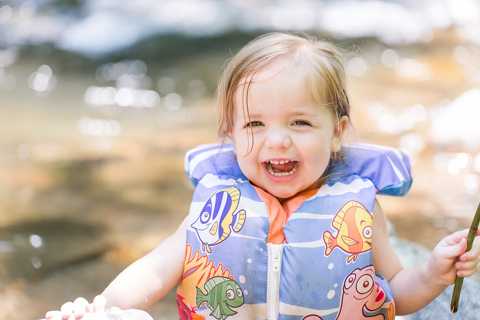 Nantahala River little girl in life jacket smiling big holding a stick photo