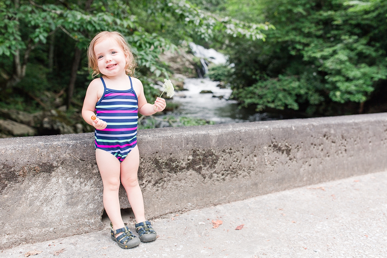 Nantahala River little girl in front of waterfall on a bridge holding a flower in her swim suit photo