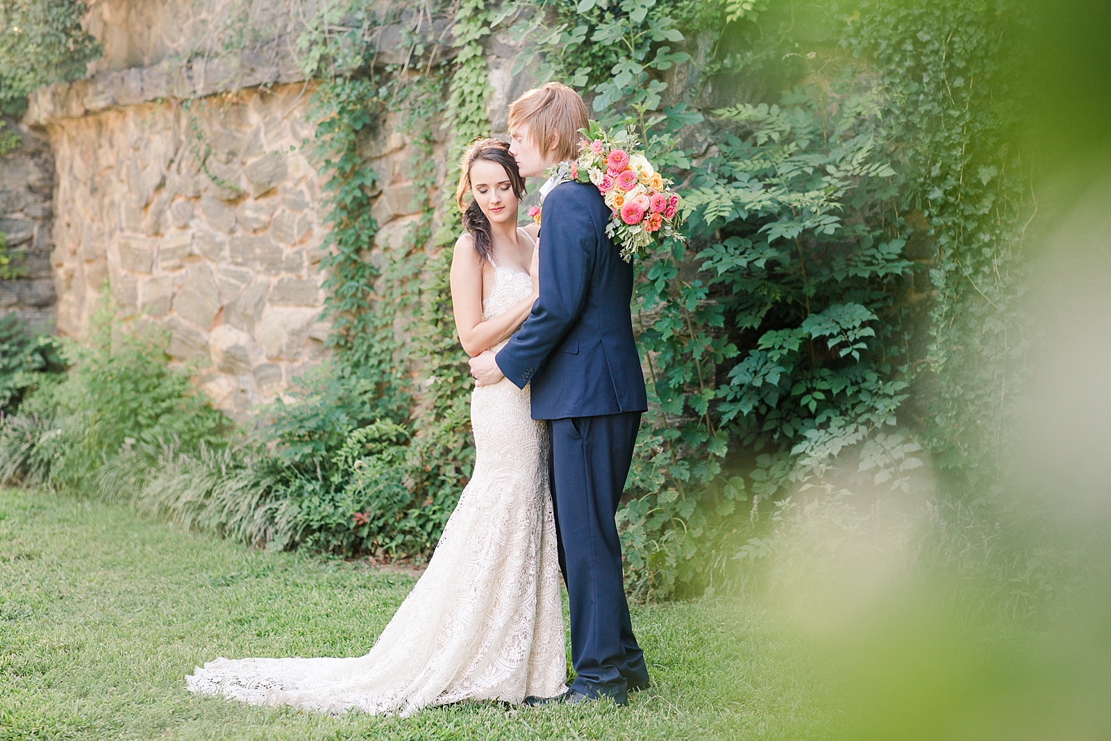 Atlanta Georgia Elopement Groom kissing bride on the head in front of a stack stone wall covered in ivy Photo