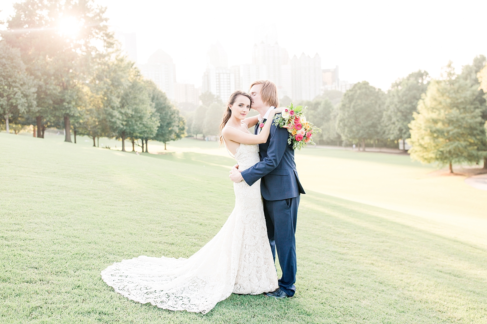Atlanta Georgia Elopement Groom kissing bride on the head in Piedmont park field with Atlanta skyline backdrop Photo