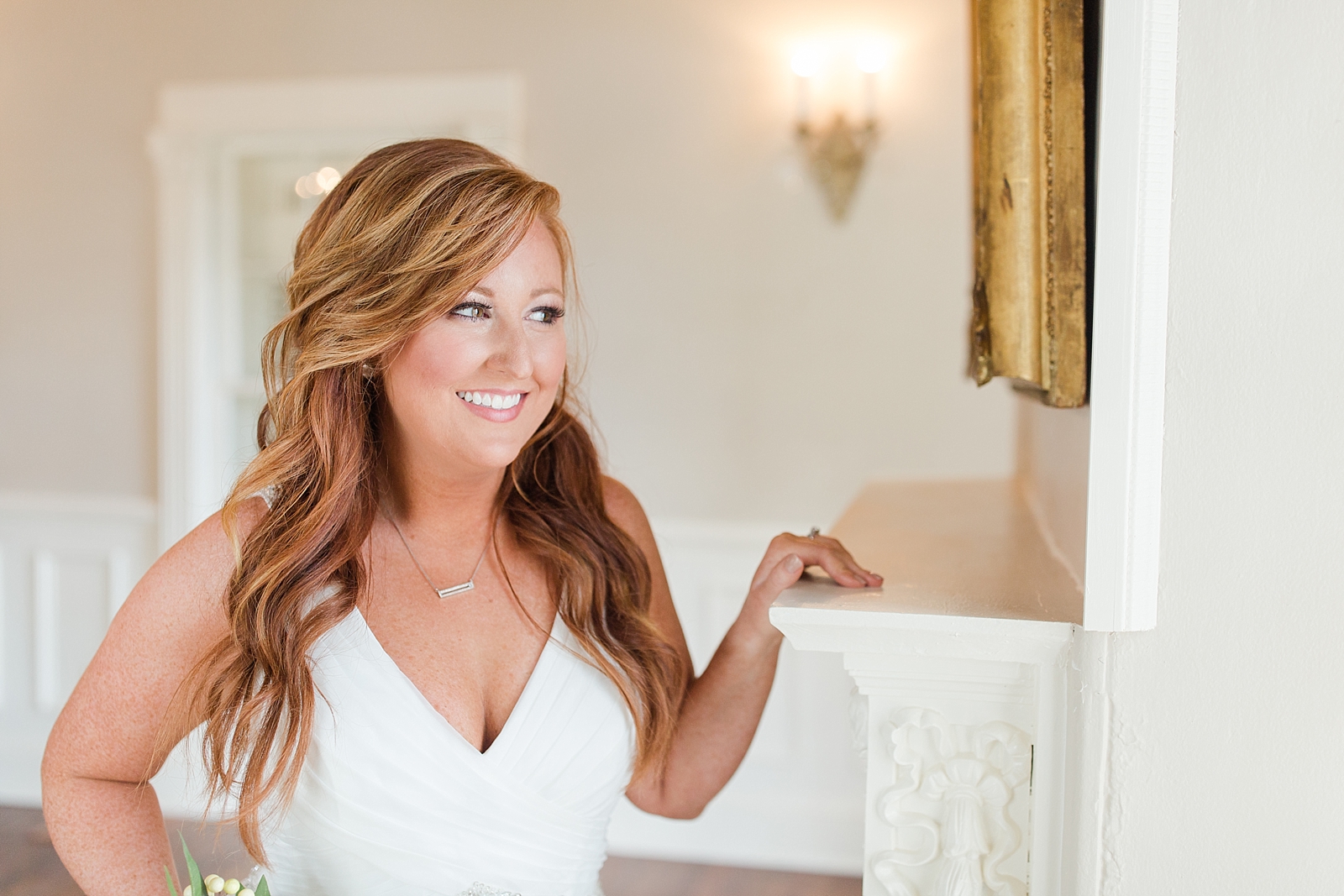 Dahlonega Wedding Venue Bride holding onto the fireplace mantle looking out the window smiling Photo