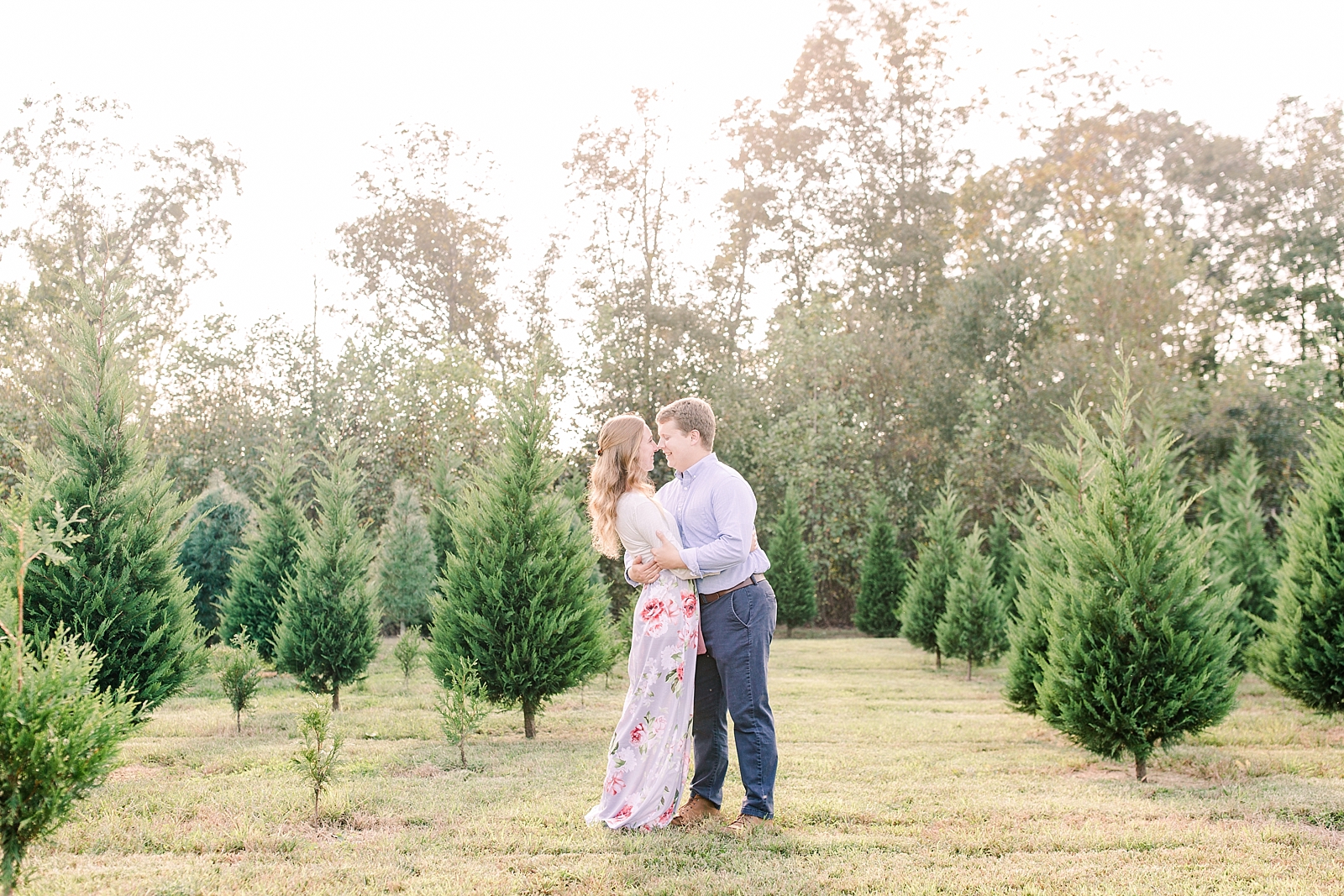 Charlotte Engagement Couple Smiling at each other in Christmas trees Photo