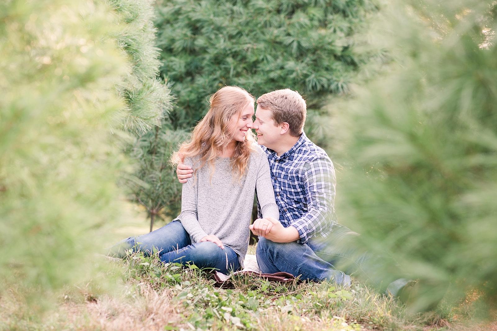 Charlotte Engagement Couple smiling nose to nose in Christmas trees Photo