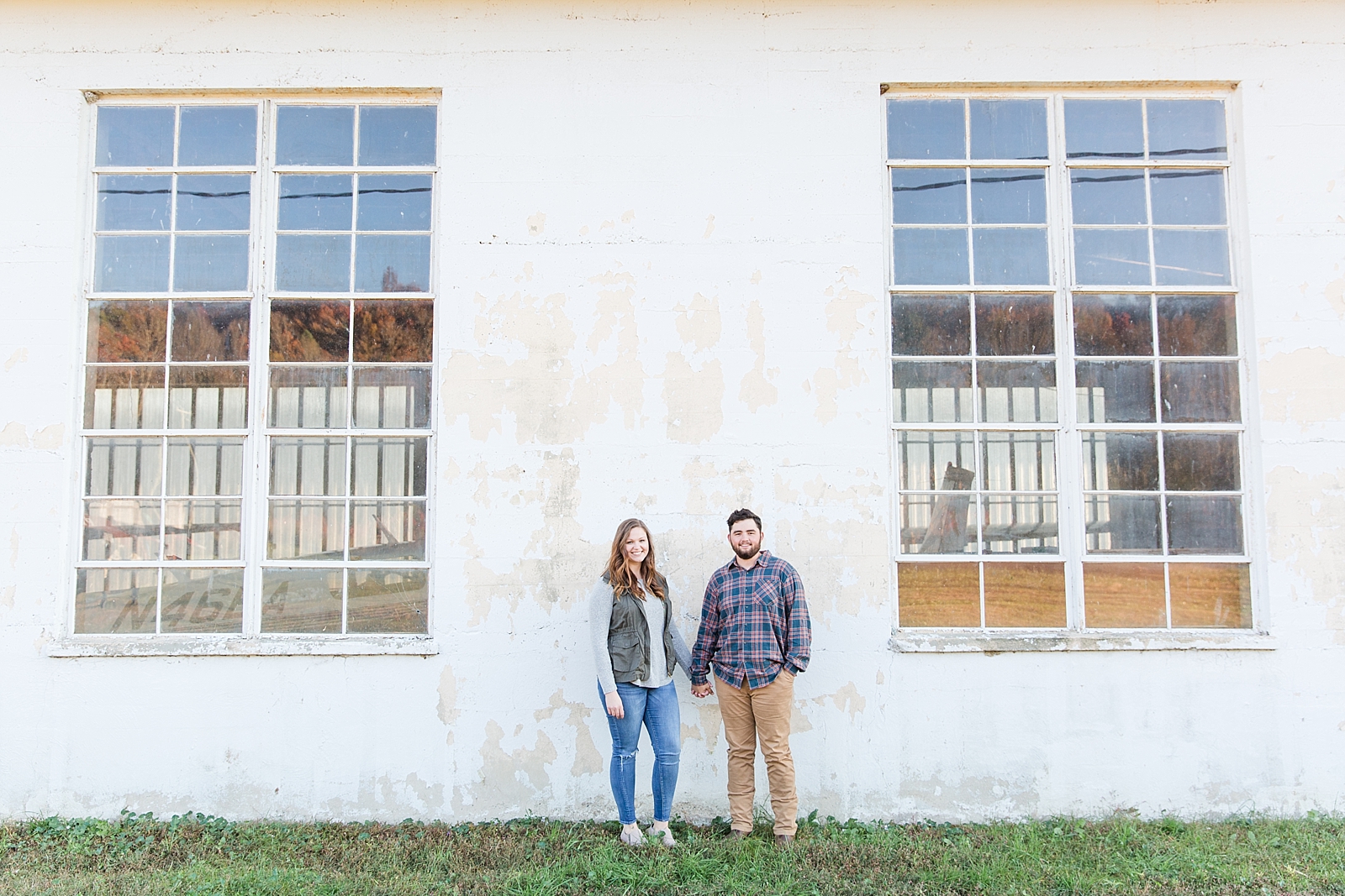 North Carolina Mountains Engagement couple in front of old building with big windows holding hands Photo