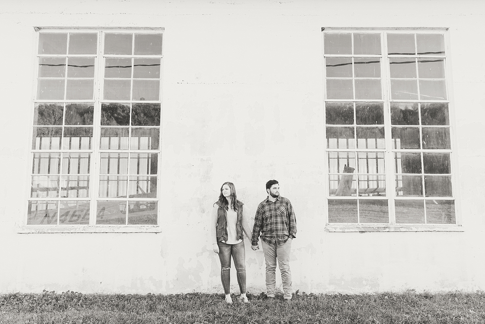 North Carolina Mountains Engagement Black and White of couple holding hands in front of building with large windows Photo