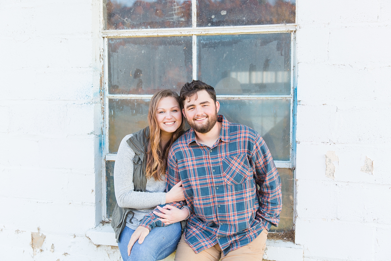 North Carolina Mountains Engagement couple smiling at the camera in front of a window Photo