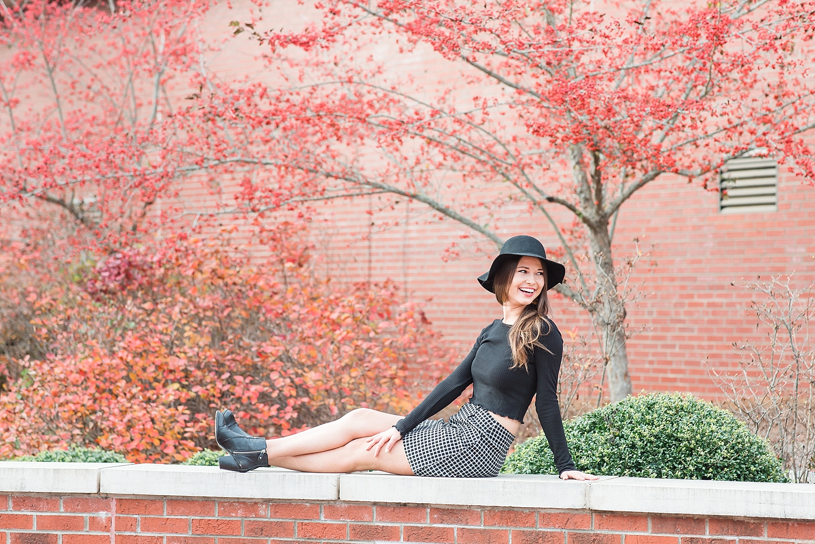 Western Carolina University Senior Sierra smiling over her shoulder sitting on brick wall Photo