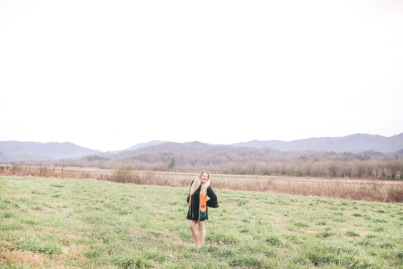 Kennesaw State University Senior Session Rachel in field with mountains in background smiling over her shoulder photo