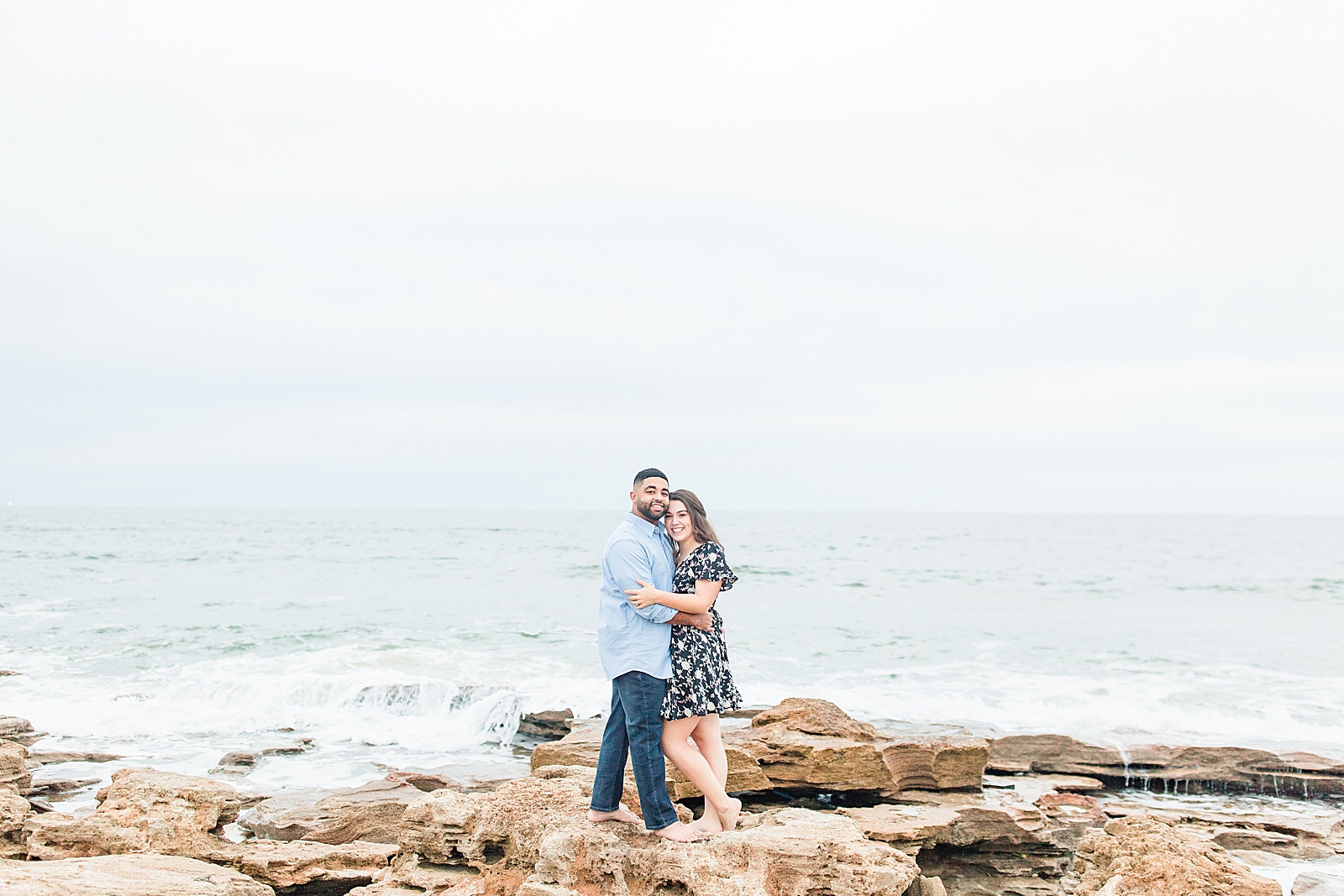St. Augustine Engagement Couple hugging smiling at camera on rocks at beach Photo