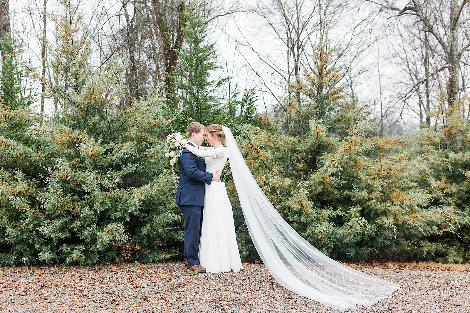 Charlotte Wedding Bride and Groom Nose to nose in front of Evergreens at Riverwood Manor Venue Photo