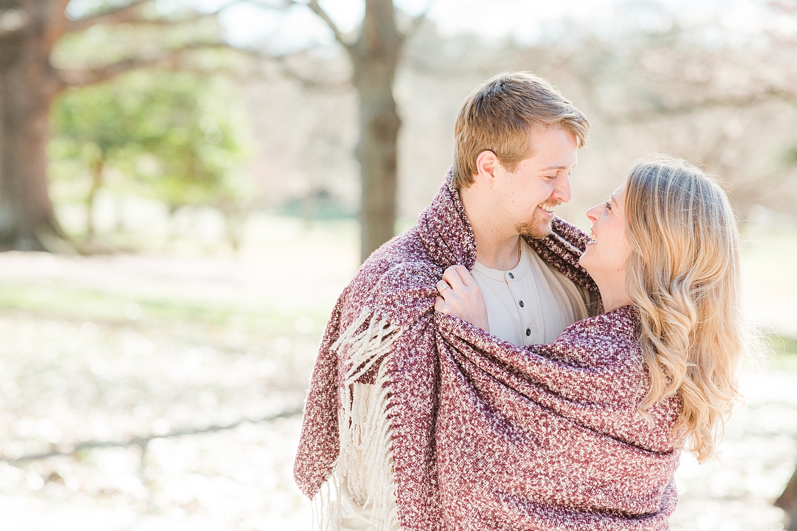 Winston-Salem Engagement Session Katie and Chris Smiling at each other wrapped in a blanket photo