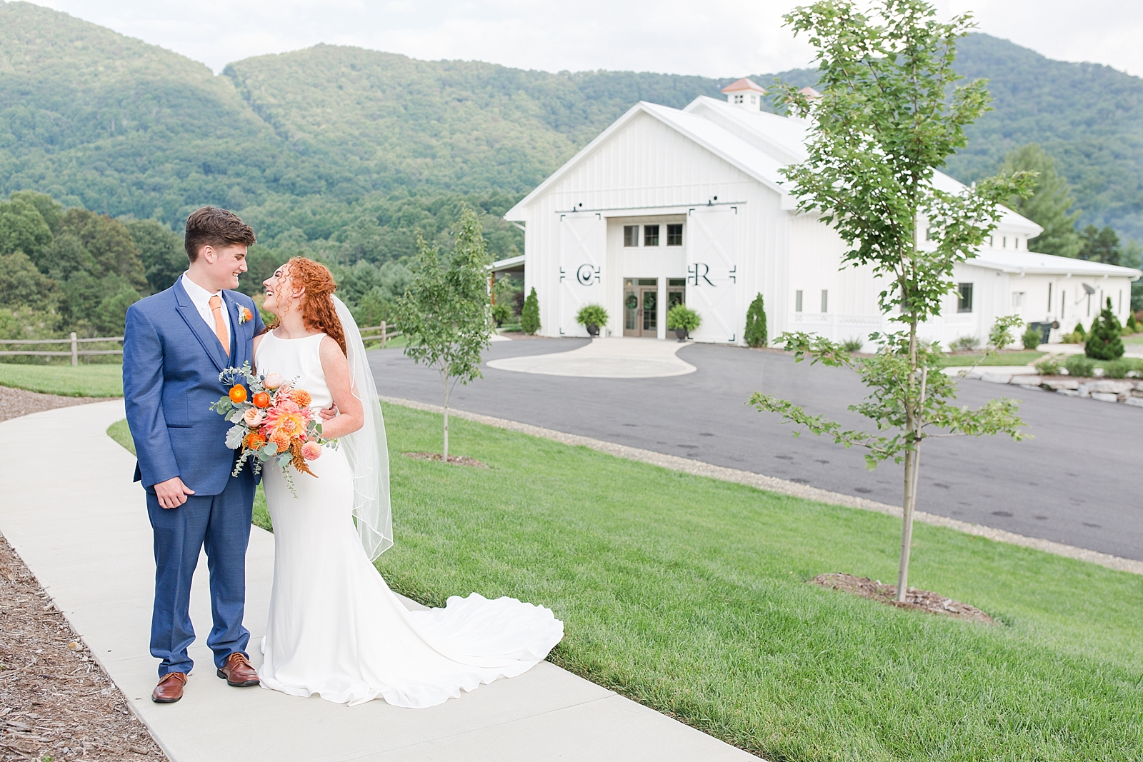 Chestnut Ridge Wedding bride and groom laughing at each other in front of white barn Photo