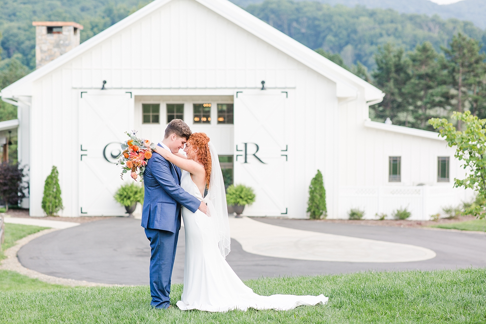 Chestnut Ridge Wedding bride and groom nose to nose on hill in front of white wedding venue Photo