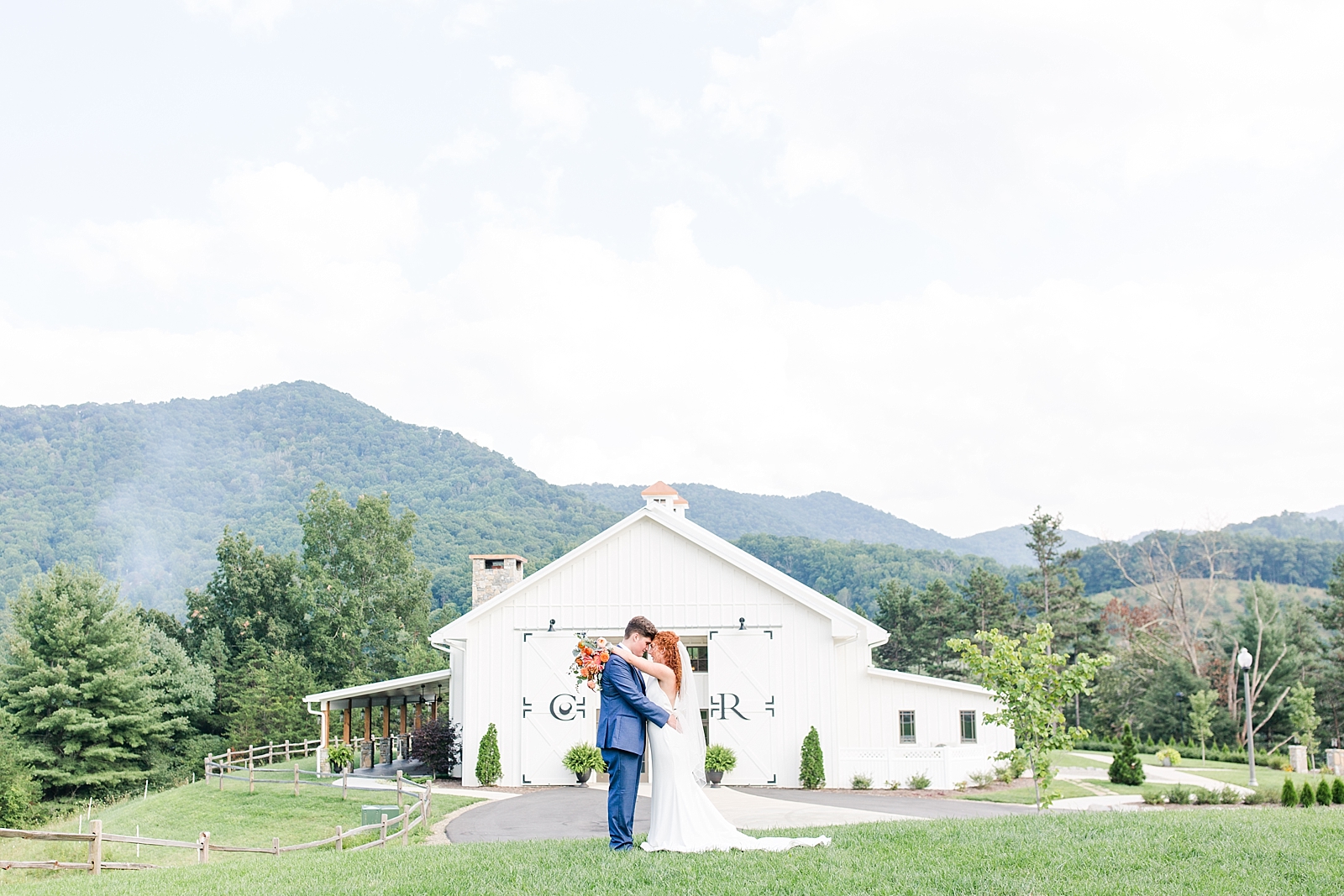 Chestnut Ridge Wedding bride and groom hugging in front of white barn Photo