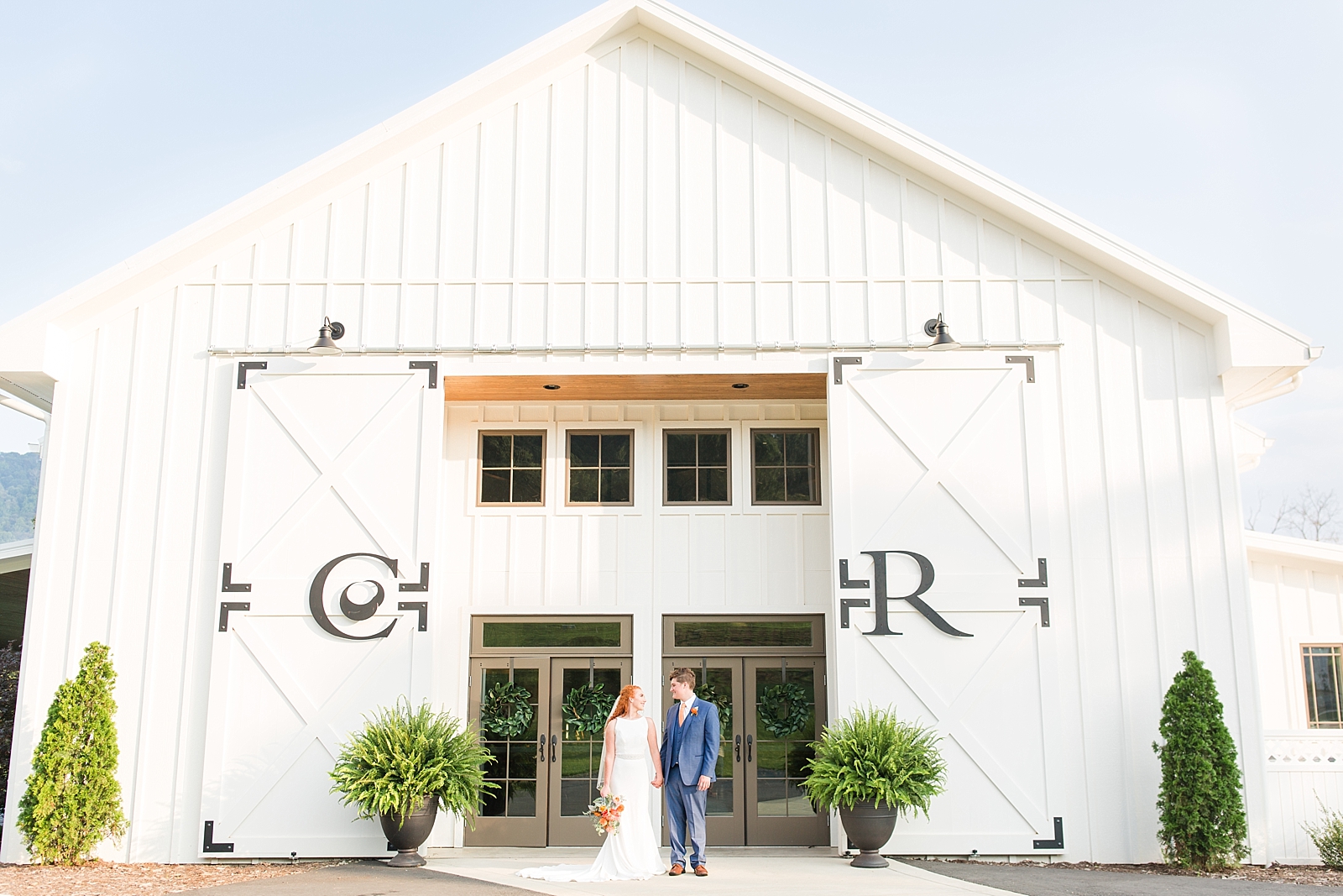Chestnut Ridge Wedding bride and groom holding hands in front of white barn venue Photo