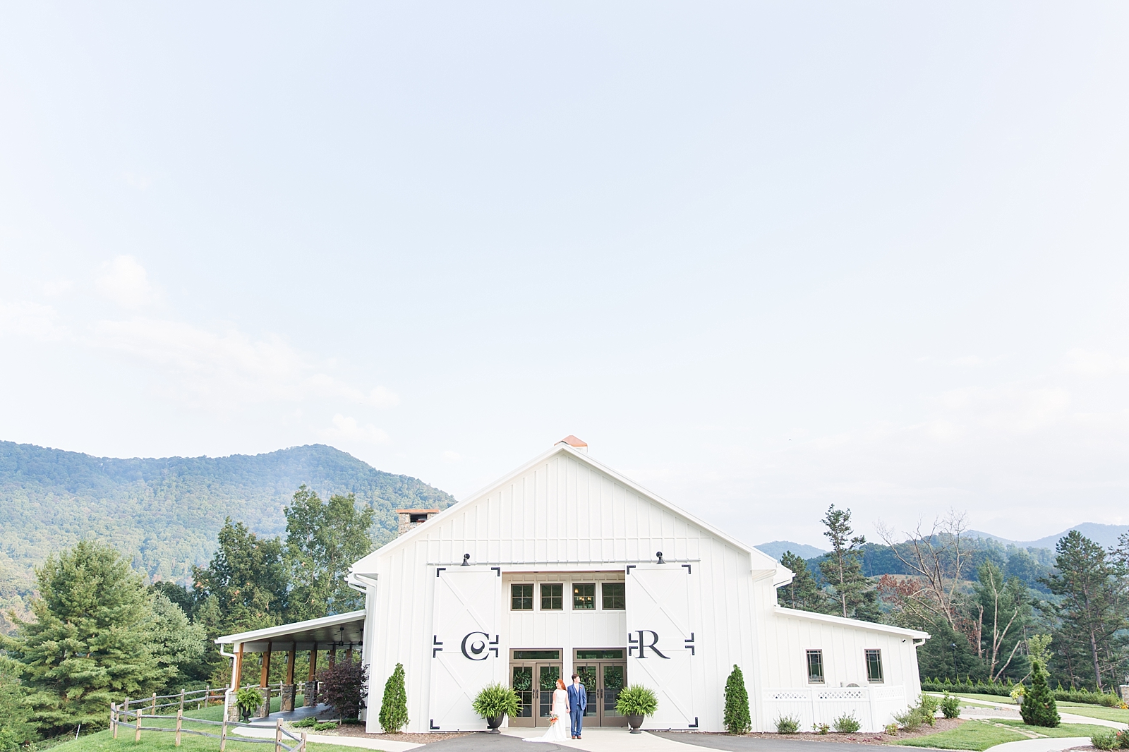 Chestnut Ridge Wedding bride and groom looking opposite directions in front of white barn wedding venue Photo