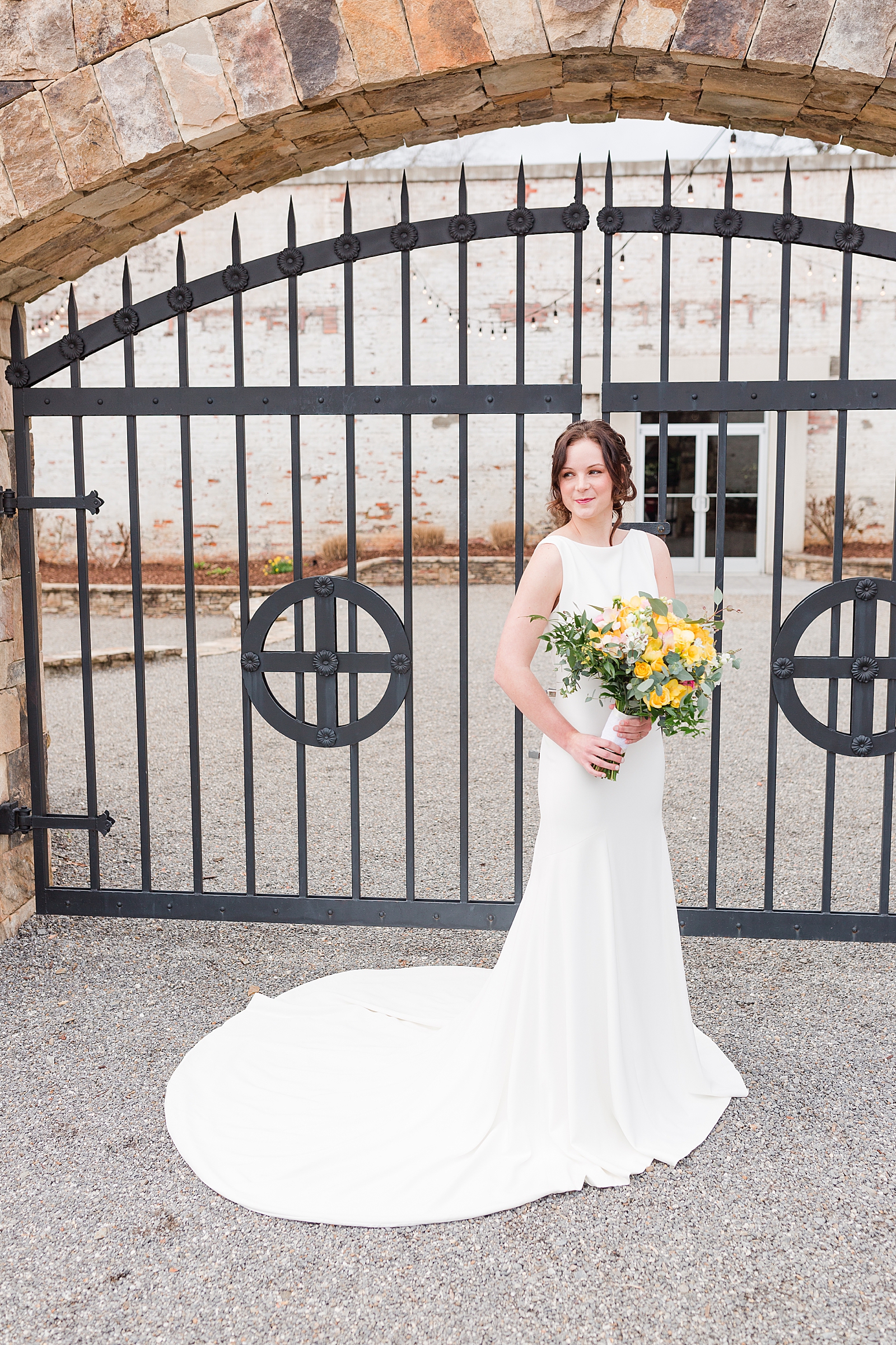 Hackney Warehouse Spring Bridal Session Bride in front of Iron Gates with yellow bouquet Photo