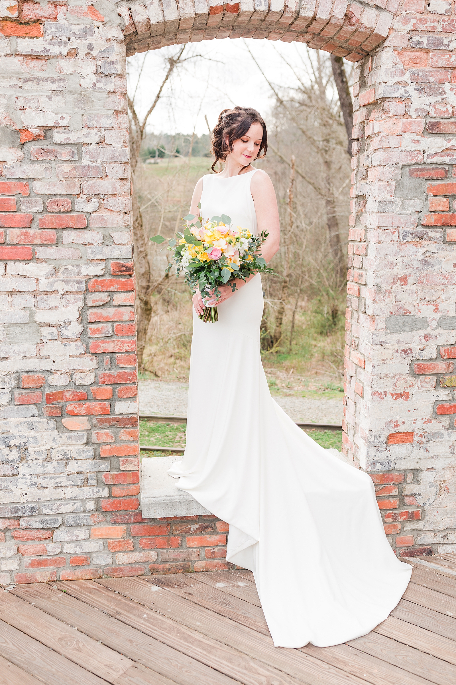 Hackney Warehouse Spring Bridal Session Bride standing in brick window looking down over her shoulder Photo