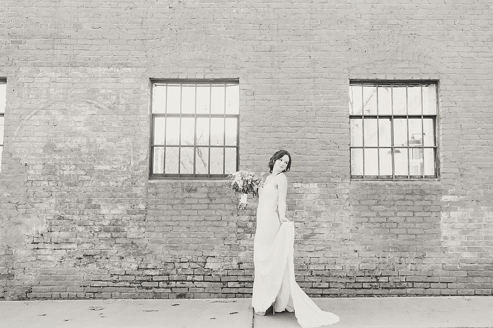 Hackney Warehouse Spring Bridal Session Black and White of bride twirling in front of brick wall Photo