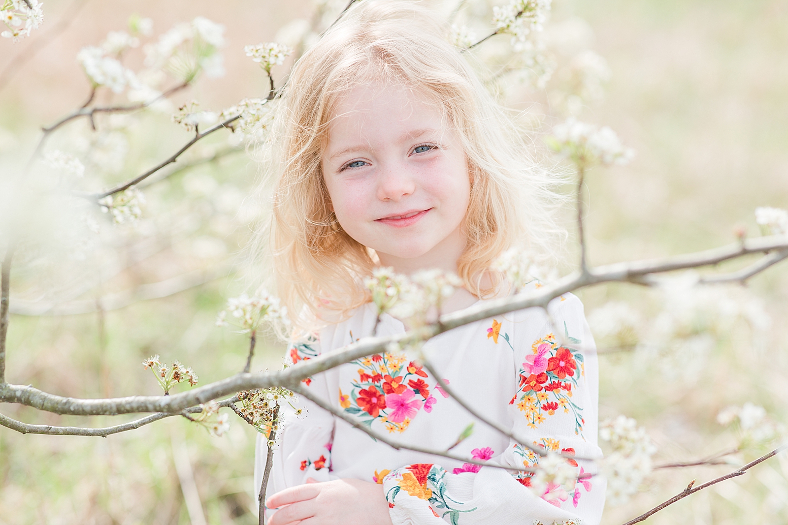 Asheville Photographer's Family blonde girl smiling at camera through trees Photo
