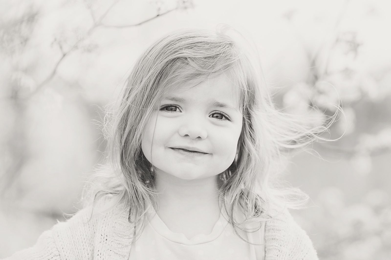 Asheville Photographer's Family Black and White of little girl smiling at the camera and hair blowing in the wind Photo