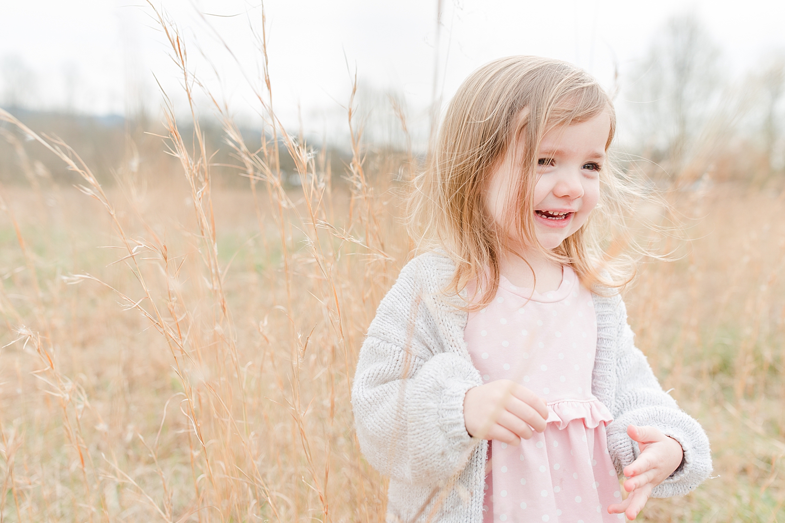 Asheville Photographer's Family Little girl in tall gras smiling with hair blowing in the wind Photo