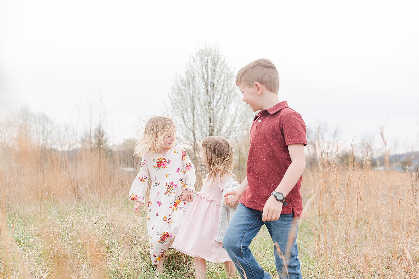 Asheville Photographer's Family Boy and two girls holding hands walking through field of tall grass Photo