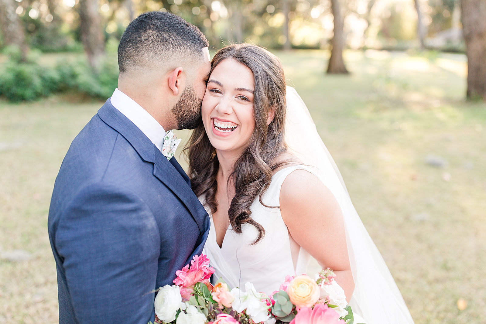 Enchanted Oaks Jacksonville Wedding Bride Smiling at Camera and Groom Nuzzling In Photo