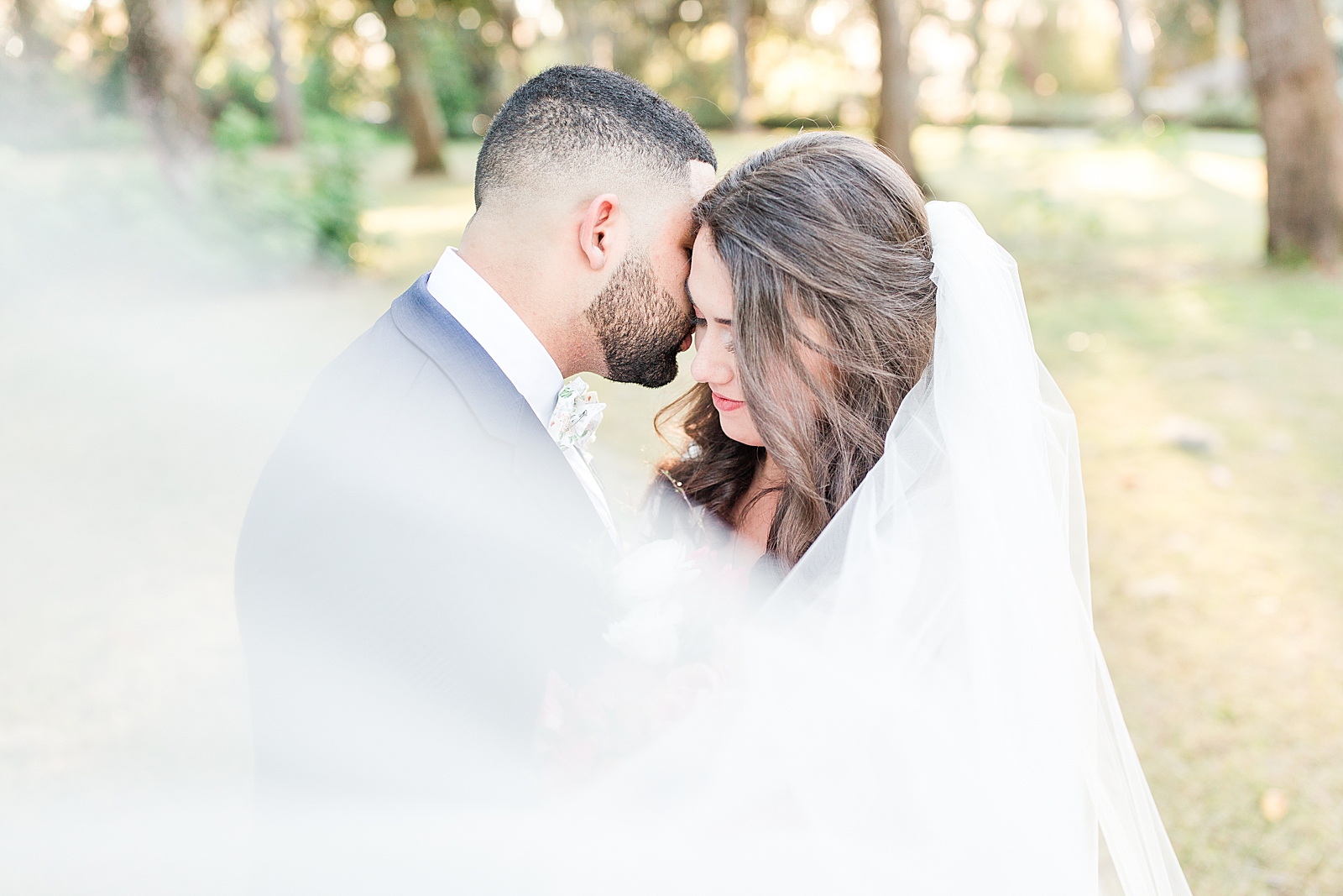 Enchanted Oaks Jacksonville Wedding Bride and Groom Snuggling with Veil Sweeping in front Photo