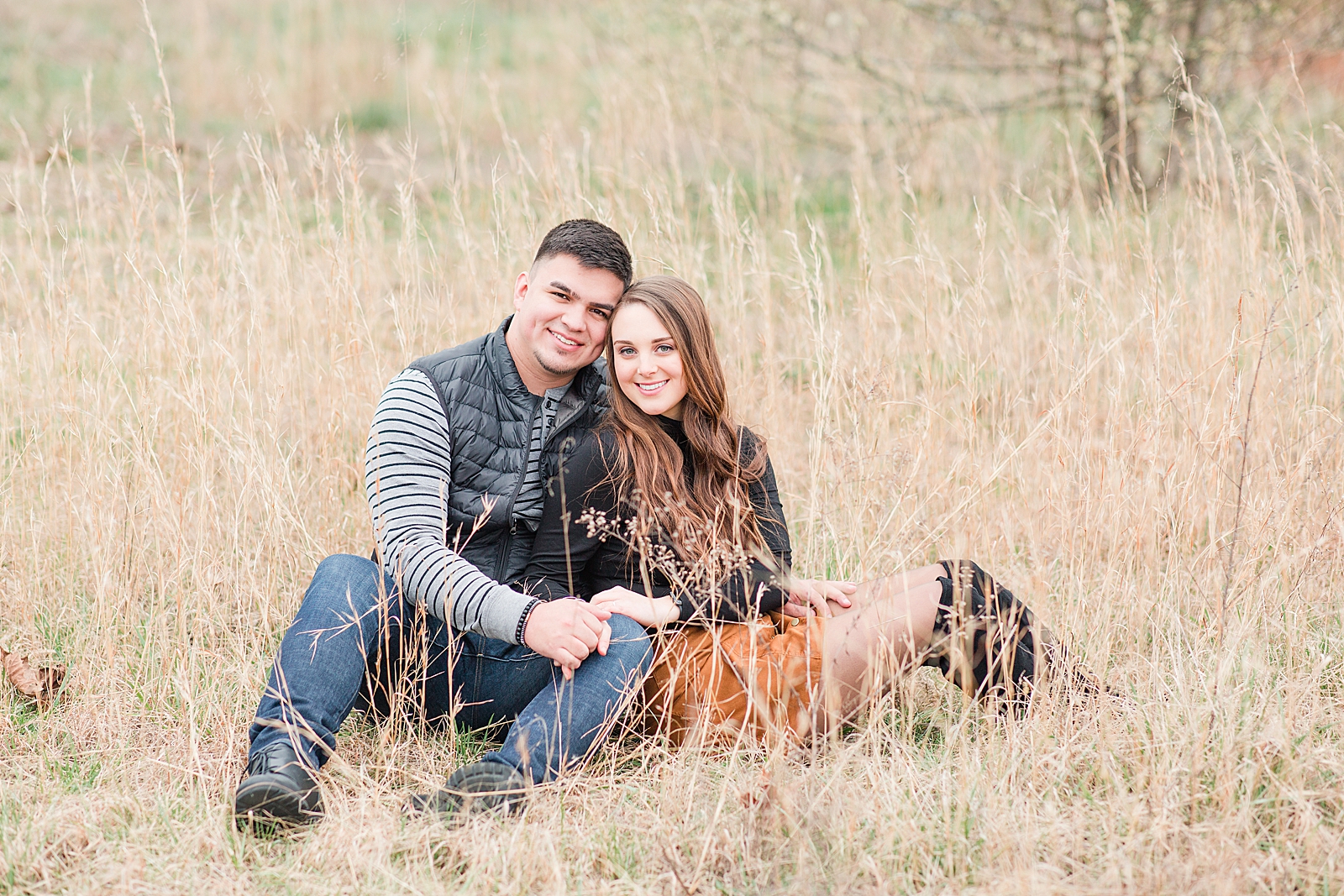 Andrews NC Spring Session Couple sitting in field of tall grass smiling at camera Photo