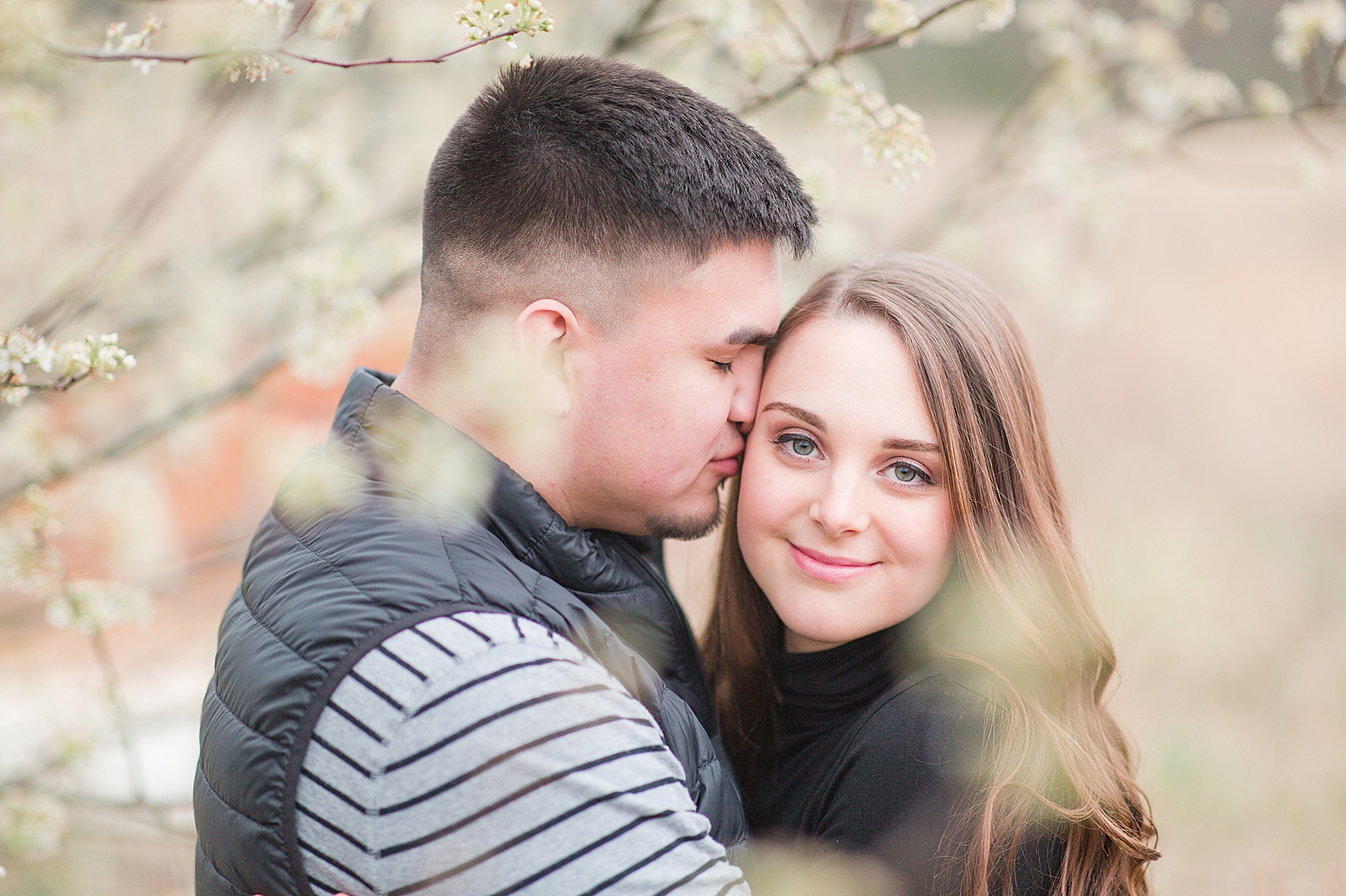 Andrews NC Spring Session Erin Smiling at camera and Spencer nuzzling in blooms from tree Photo