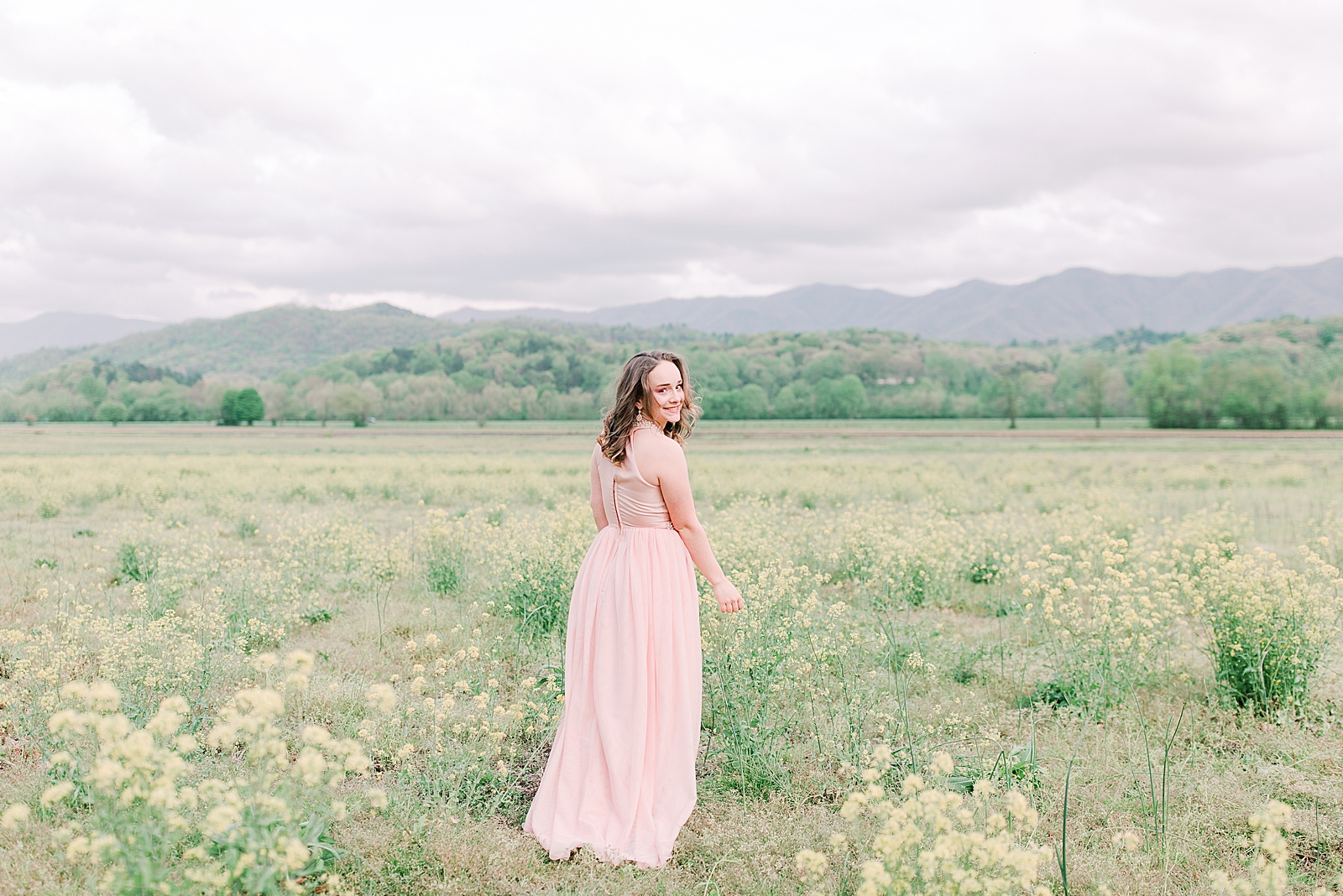 High School Senior Session Zoe smiling over her should in field of yellow flowers Photo