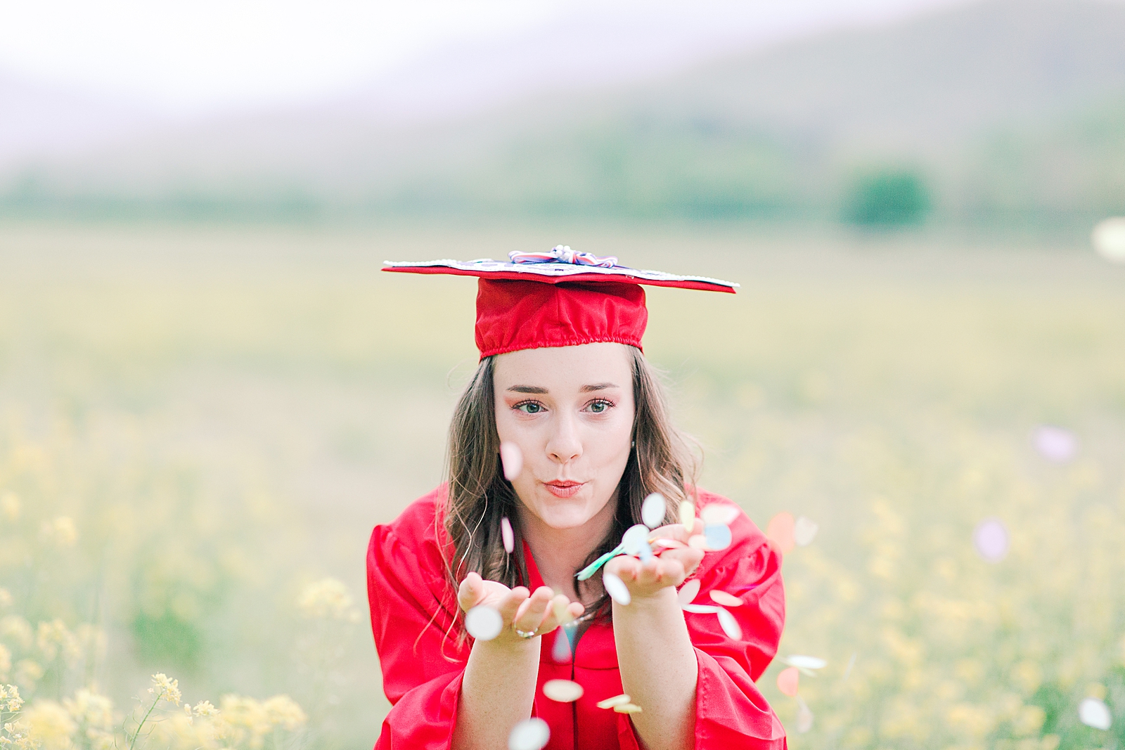 High School Senior Session Senior in red cap and gown blowing confetti Photo