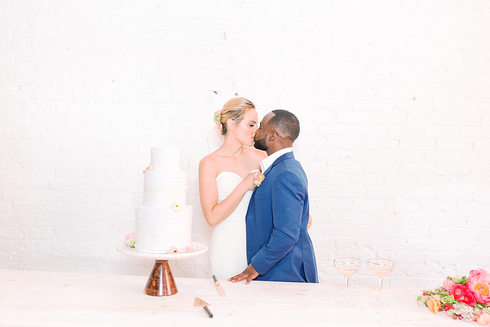Spring Brickyard Wedding Reception Bride and Groom Kissing by cake Photo