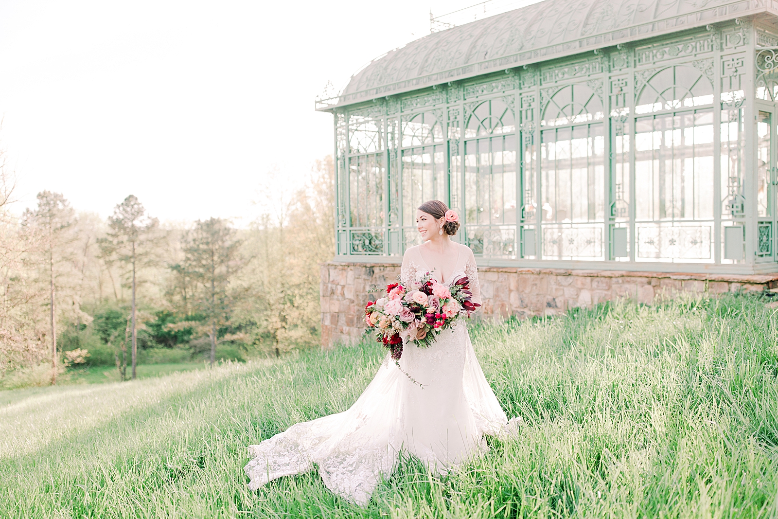2400 On The River Wedding Bride in grass smiling in front of Greenhouse Photo