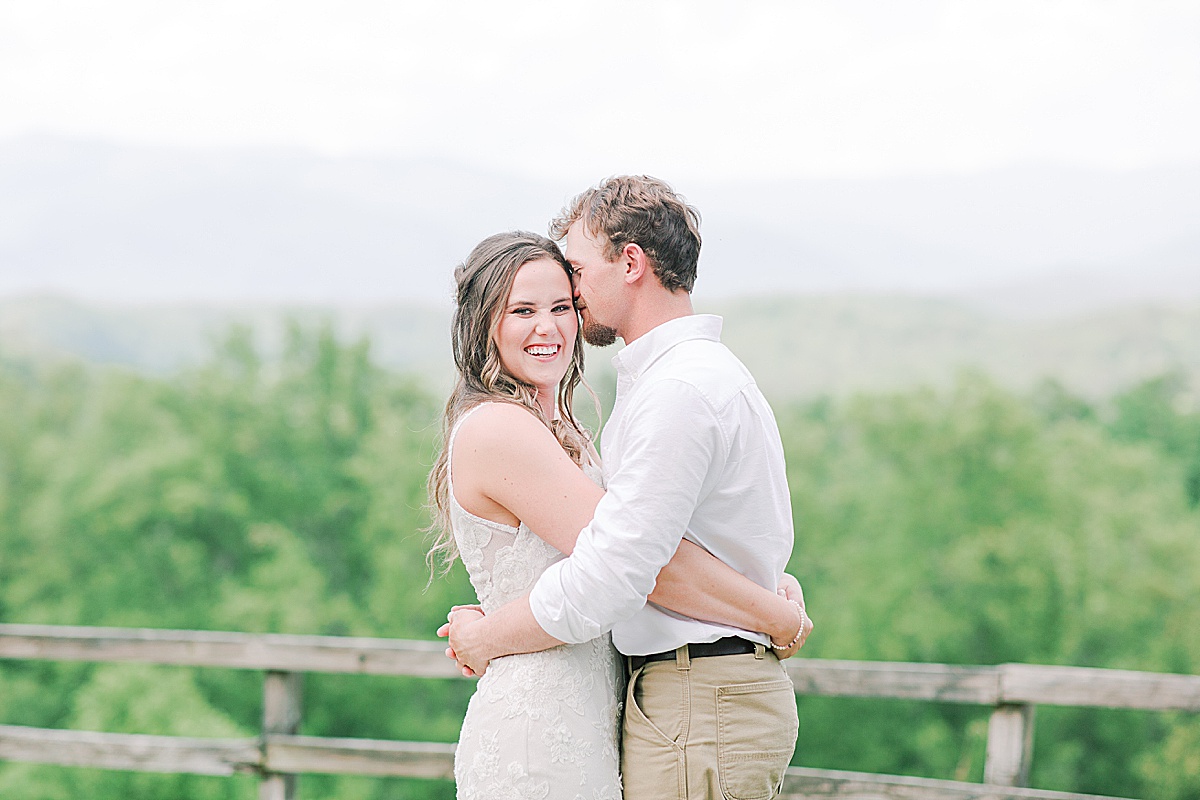 Rustic Spring Mountain Wedding Bride Giggling at Camera and Groom Nuzzling her Photo
