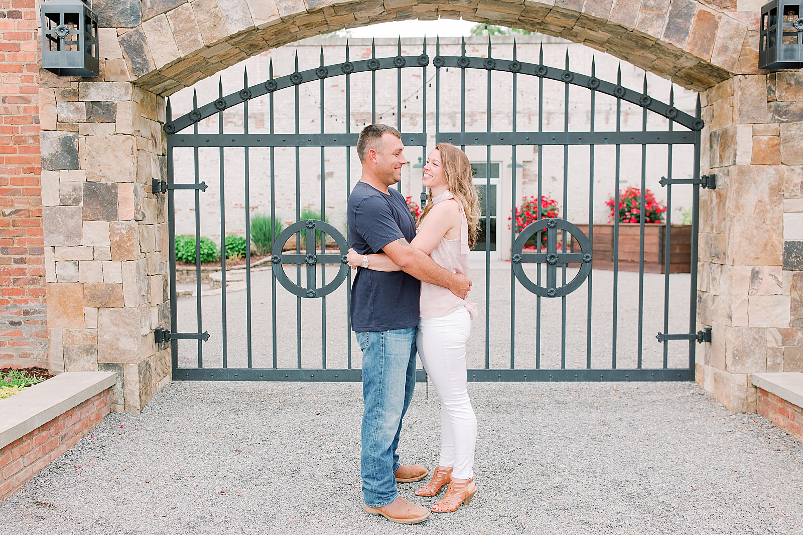 Hackney Warehouse Engagement Session Couple smiling at each other in front of iron gate Photo
