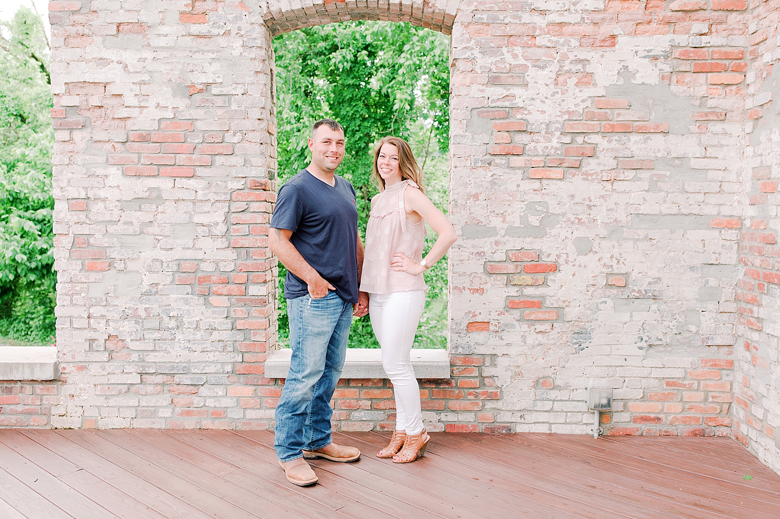 Hackney Warehouse Engagement Session Couple smiling at camera in front of brick wall Photo