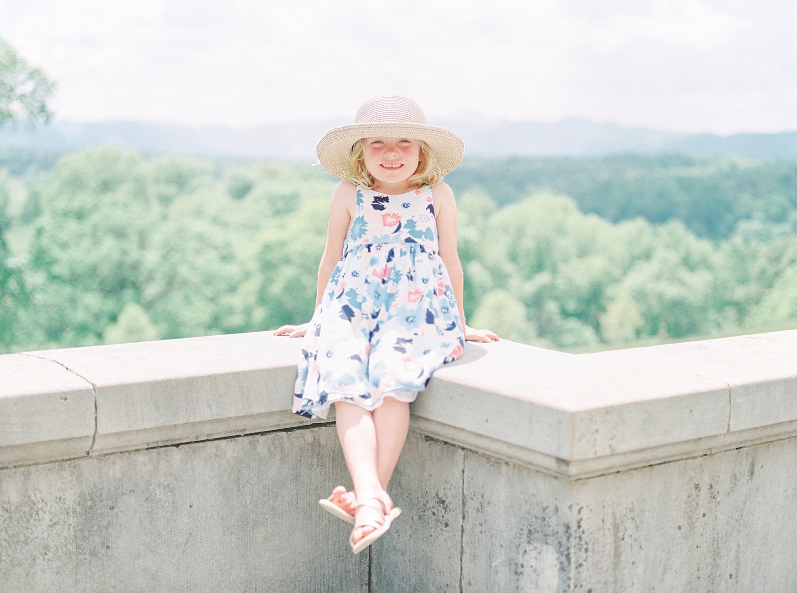 Biltmore House and Gardens Little girl sitting on wall with mountains in background Photo