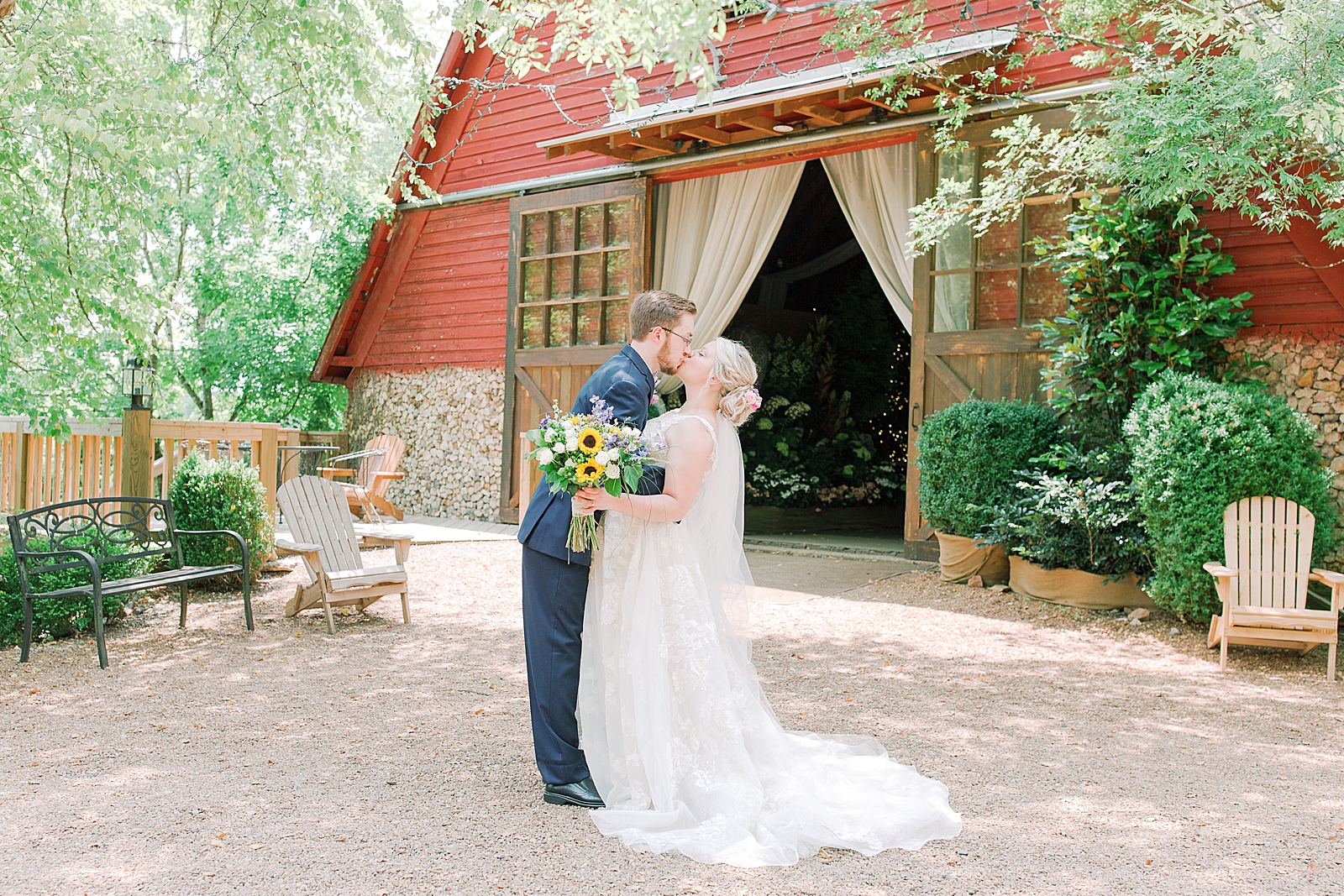 Black Fox Farms Garden Wedding Bride and Groom Kissing in Front of Red Barn Photo