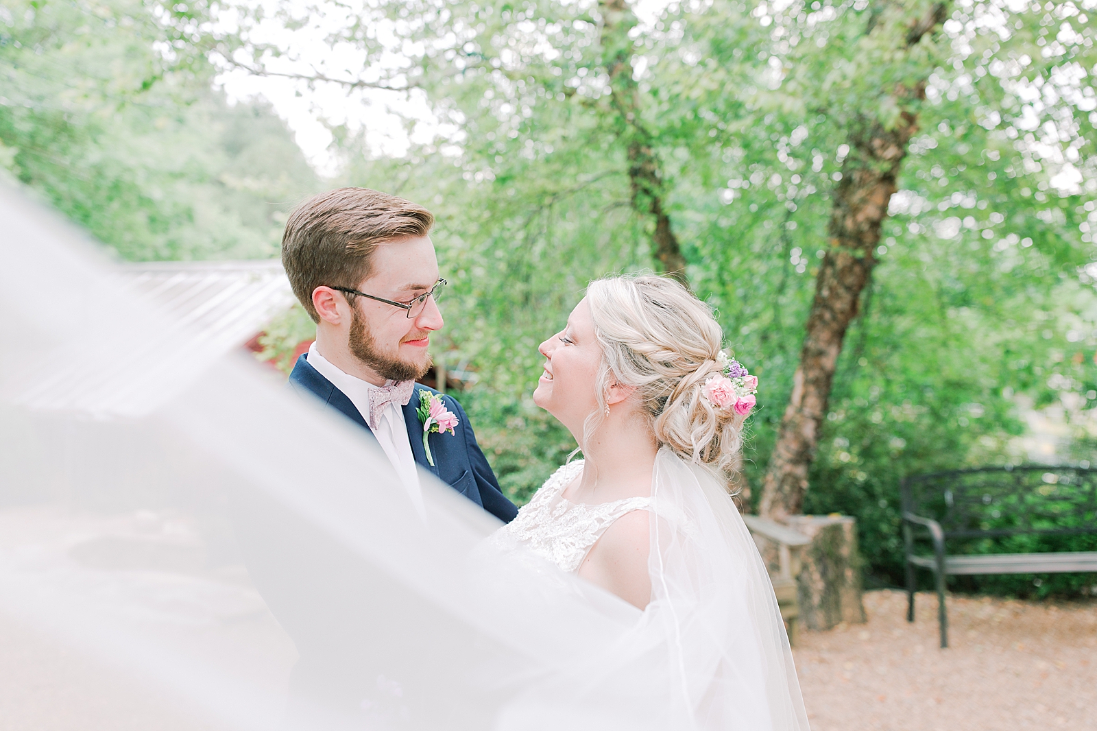 Black Fox Farms Garden Wedding Bride and Groom Smiling at Each other with Veil Sweeping in Front Photo