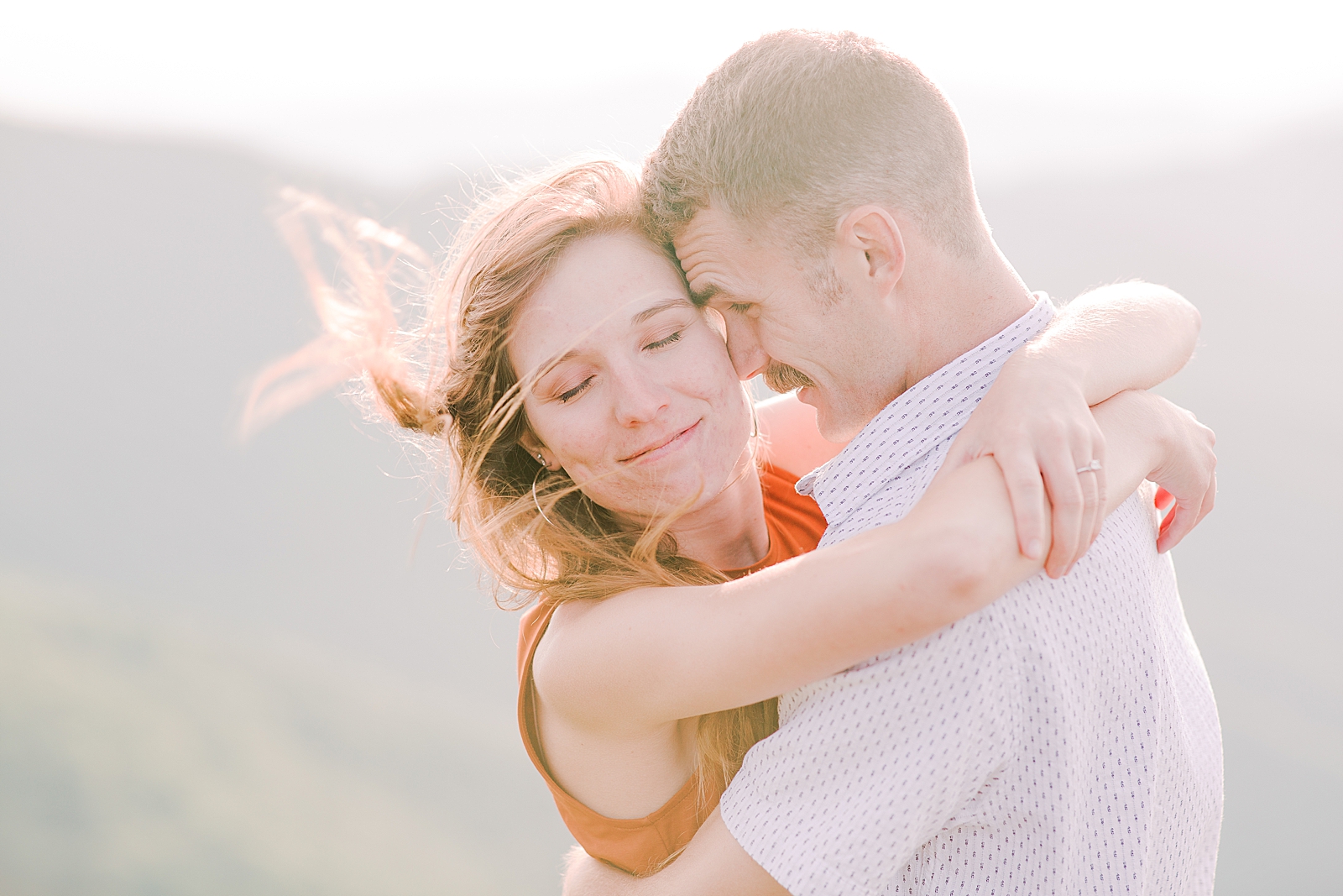 Craggy Gardens Engagement Couple Hugging with her hair blowing in front Photo