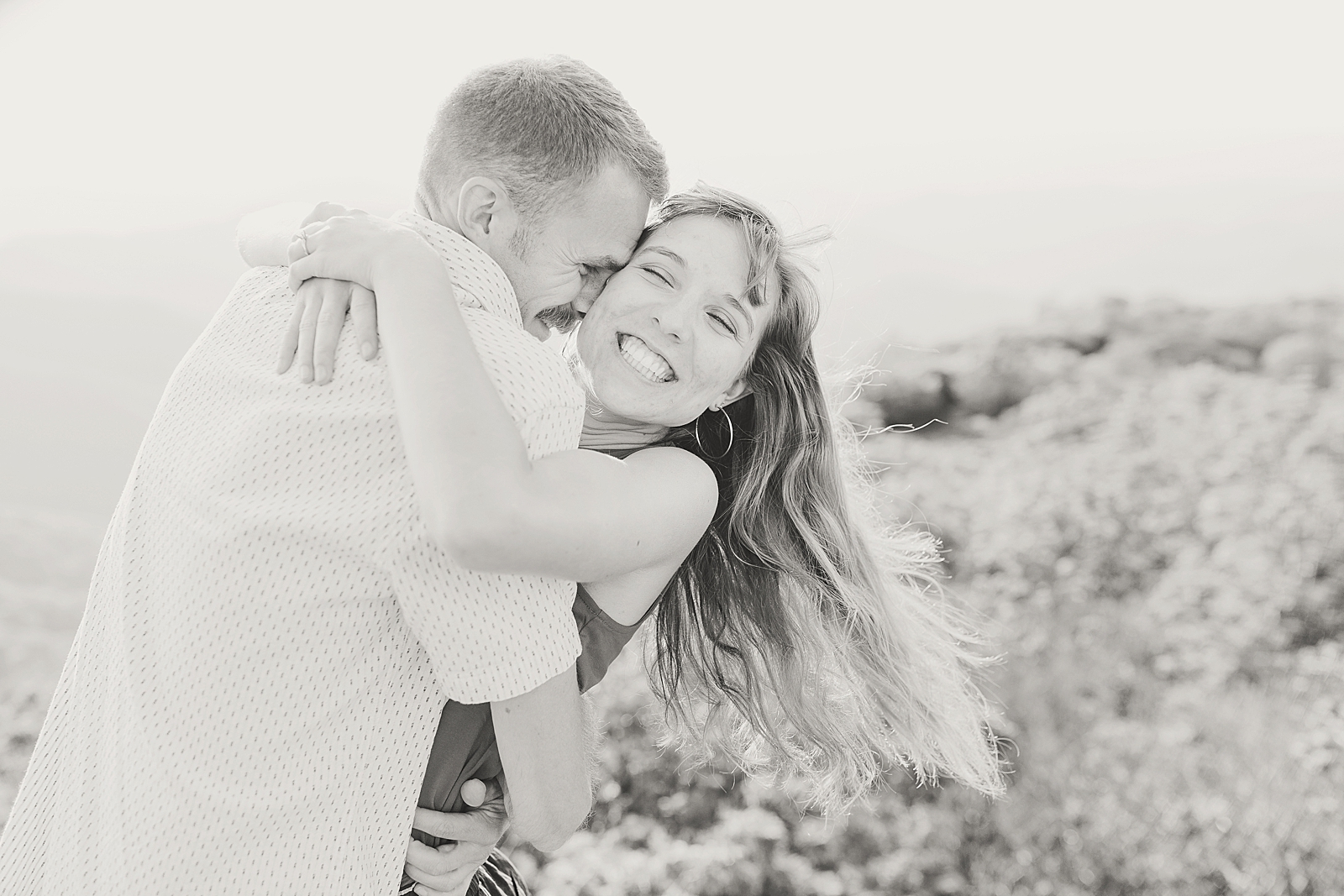 Craggy Gardens Engagement Black and White of Megan Laughing Hair Blowing in the wind hugging Ben Photo
