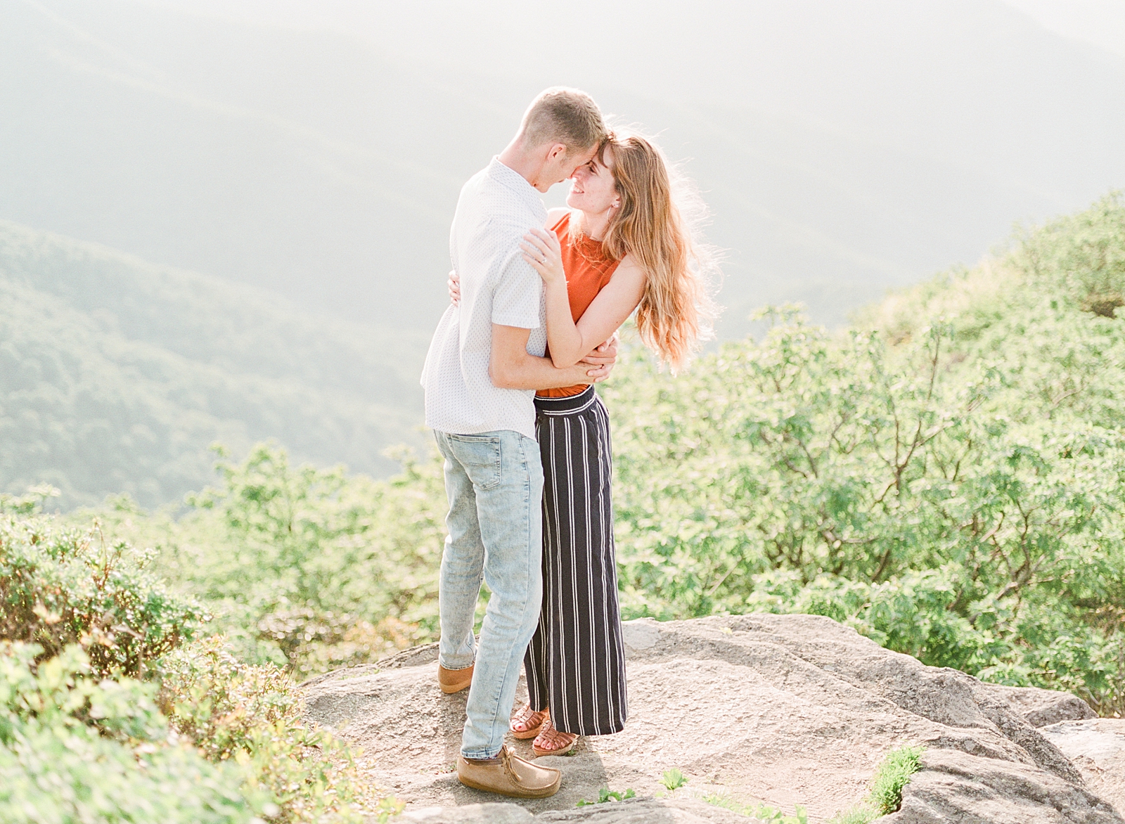 Craggy Gardens Engagement Film Photography of Couple Nose to Nose on Rock with Mountain Background Photo