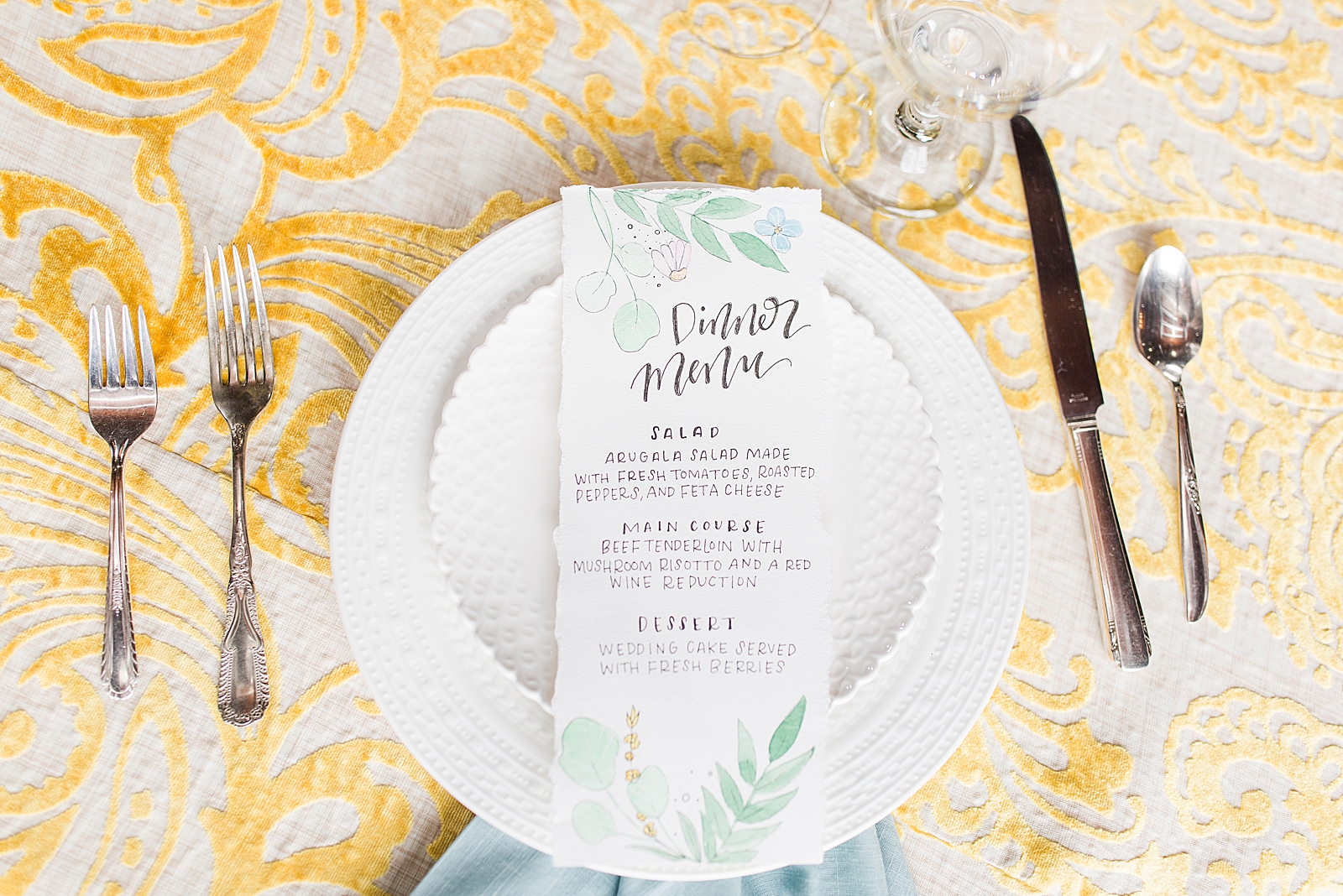 Hackney Warehouse Wedding Reception table details with yellow table cloth blue napkin and dinner menu on white plates Photo