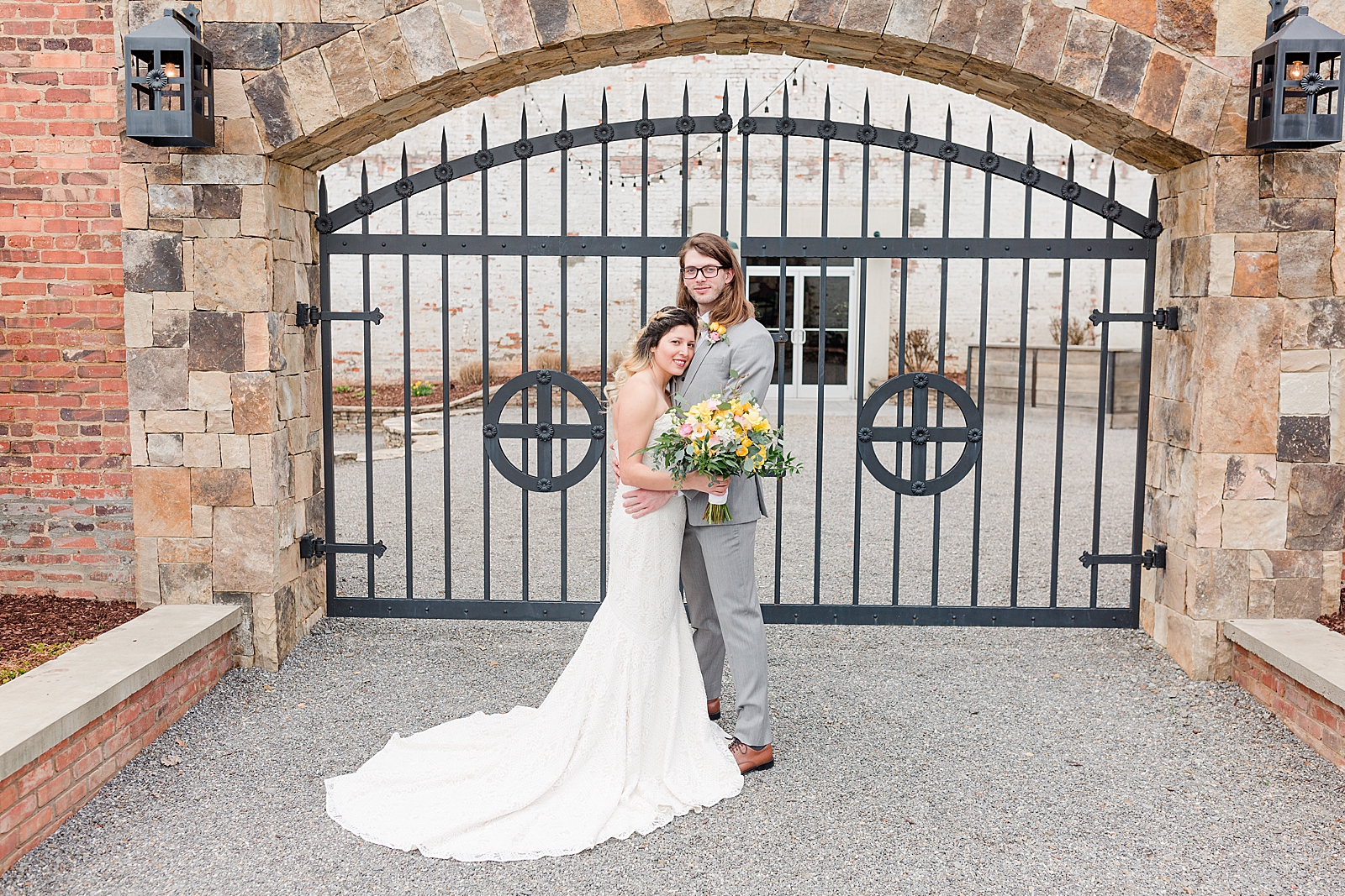 Hackney Warehouse Wedding Couple Hugging and Smiling at Camera in front of Iron Gates Photo