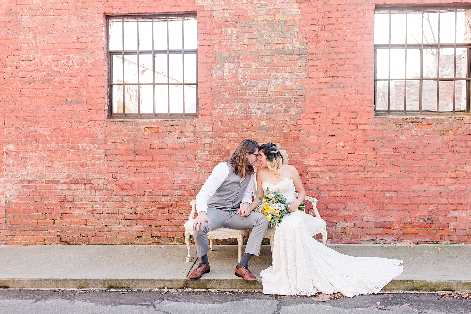 Hackney Warehouse Wedding Bride and Groom Sitting in front of Brick Wall Nose to Nose Photo