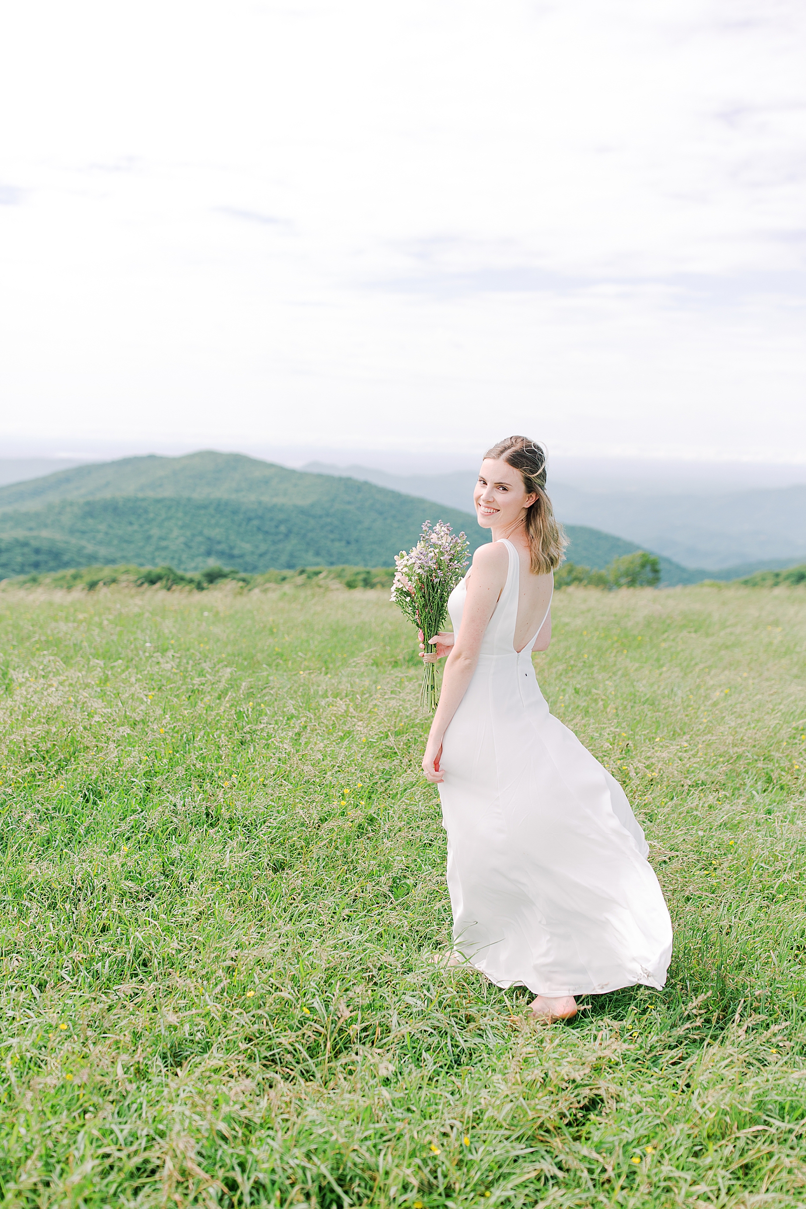 Max Patch Elopement Bride Looking Over Shoulder in Filed with Mountains Photo