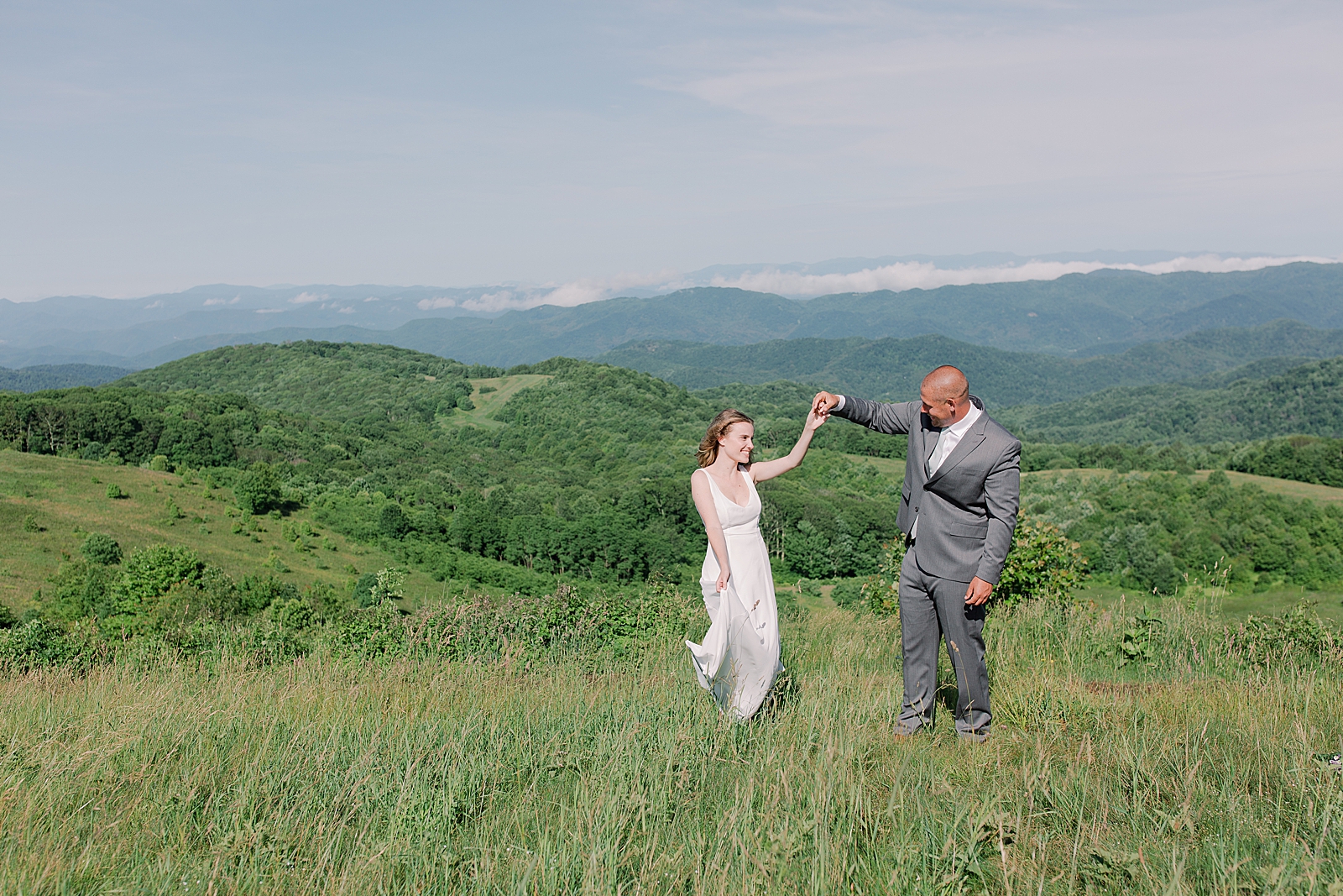 Max Patch Elopement Bride and Groom Spinning in Field Photo
